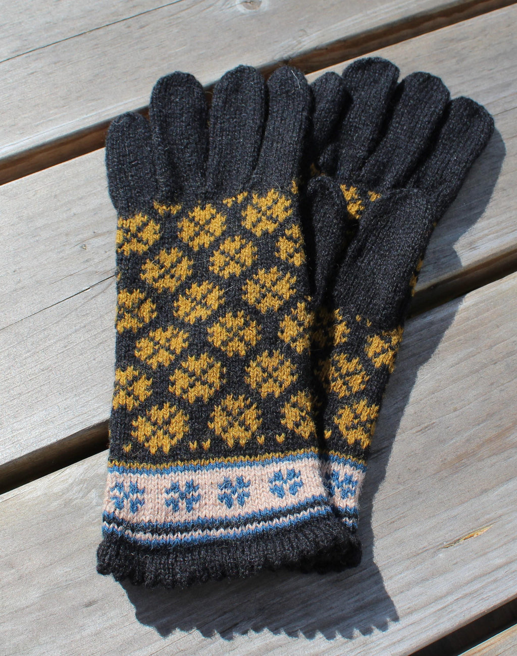 Pair of gloves with a pattern on a wooden surface