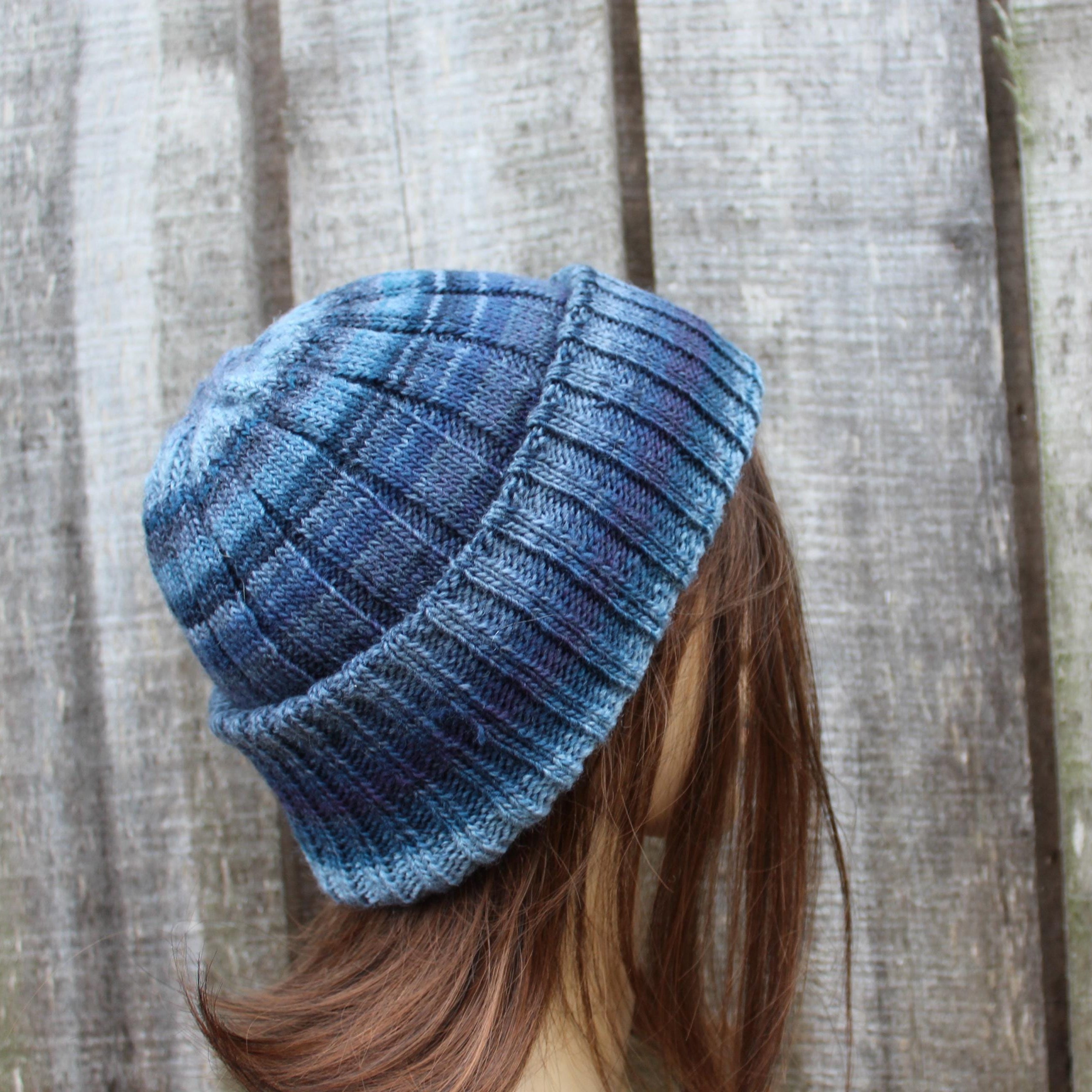 Blue knitted beanie worn by a person with wooden planks in the background