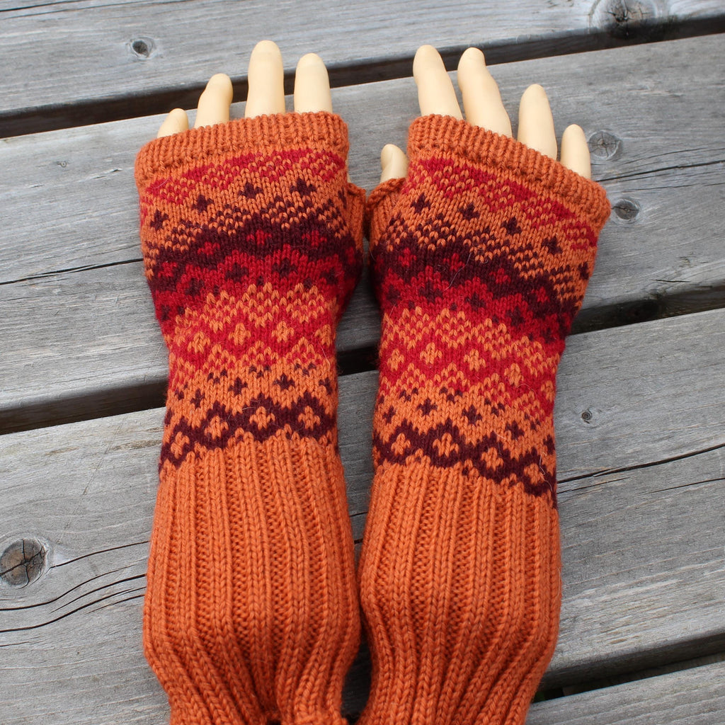 Pair of orange and red knitted fingerless gloves on a wooden surface