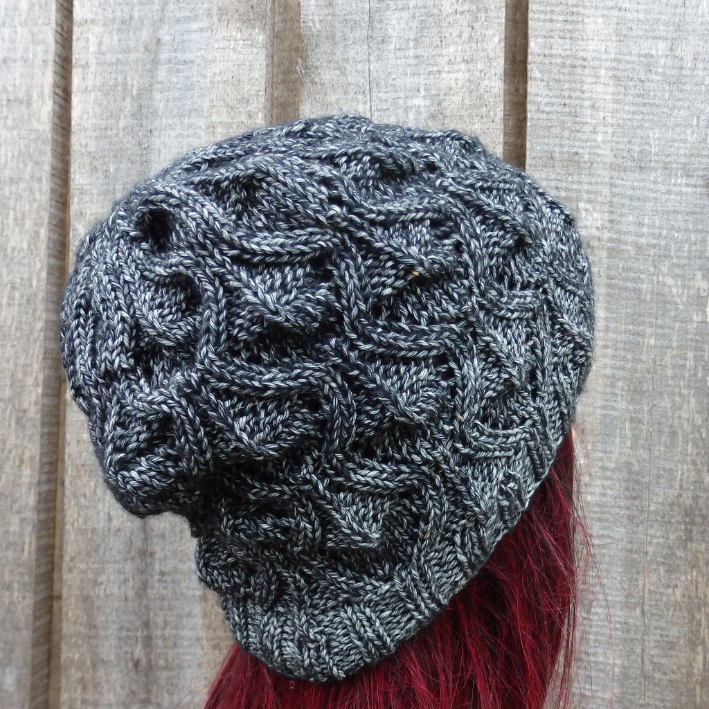 Knitted gray beanie with red hair on a wooden background
