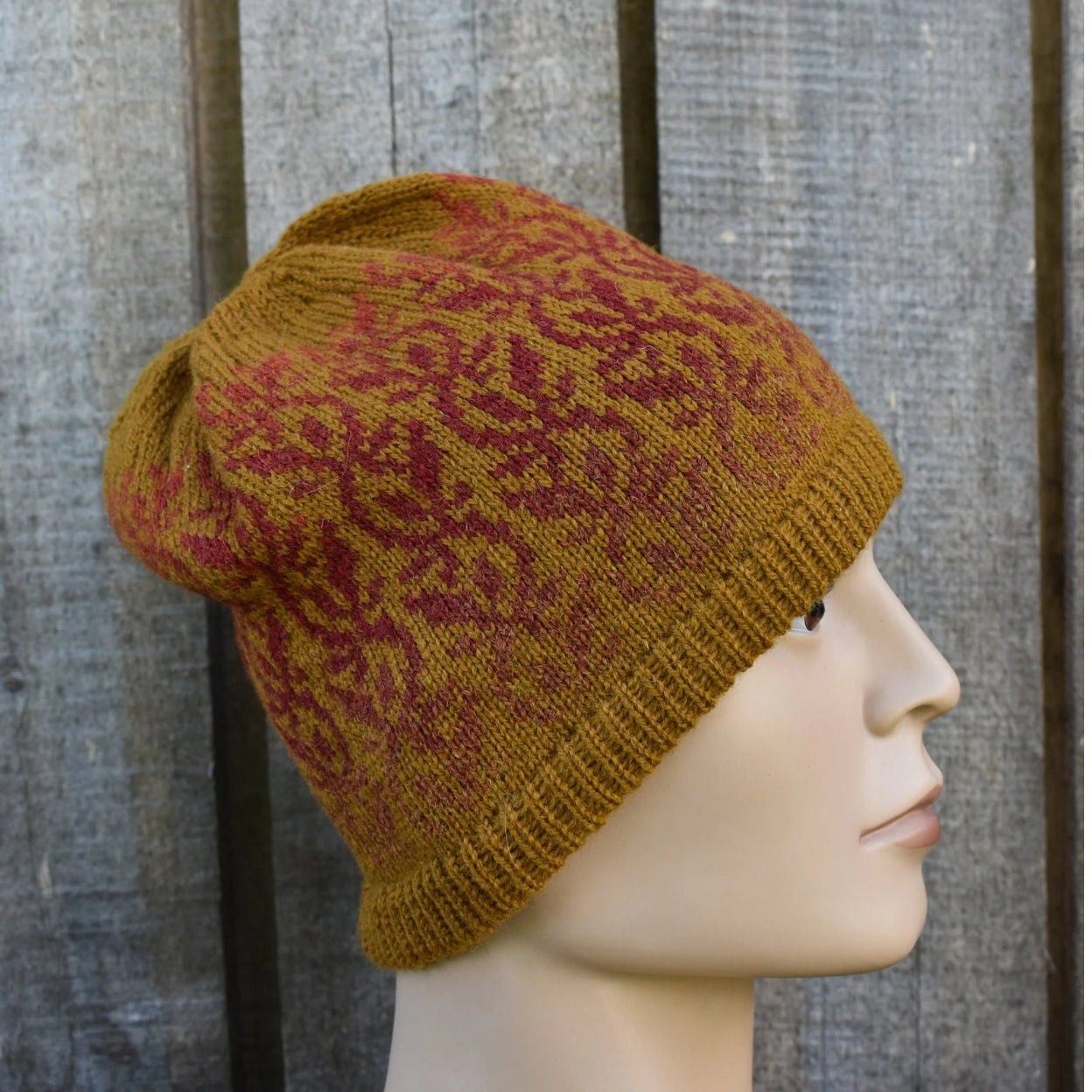 Knitted beanie with a pattern on a mannequin head against a wooden background