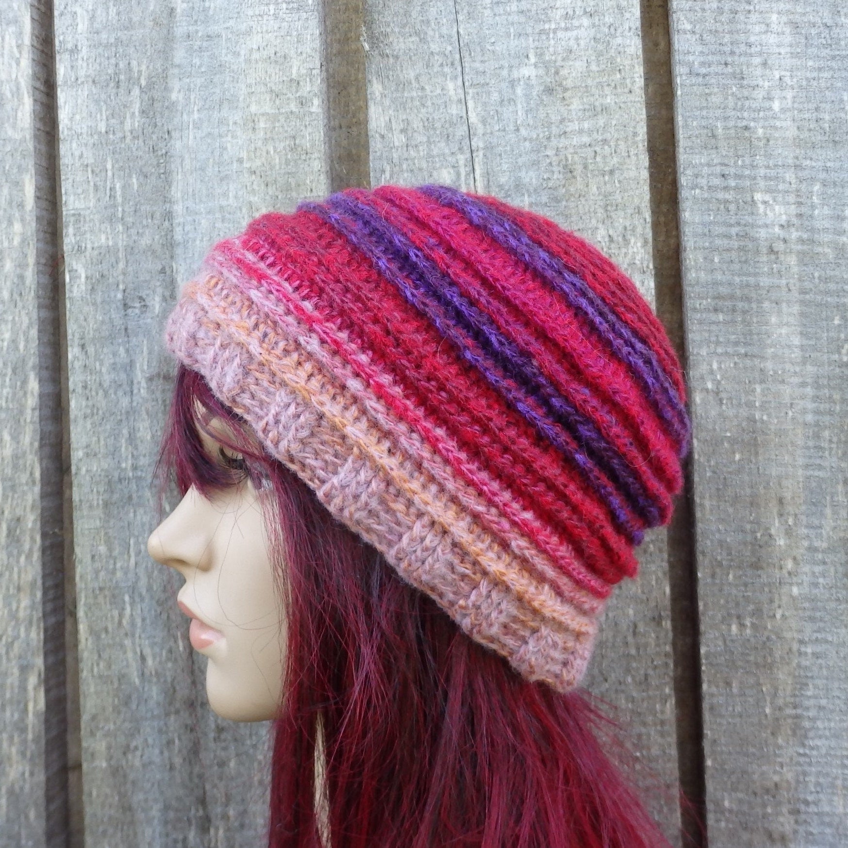 Multicolored knitted beanie on a mannequin head against a wooden background