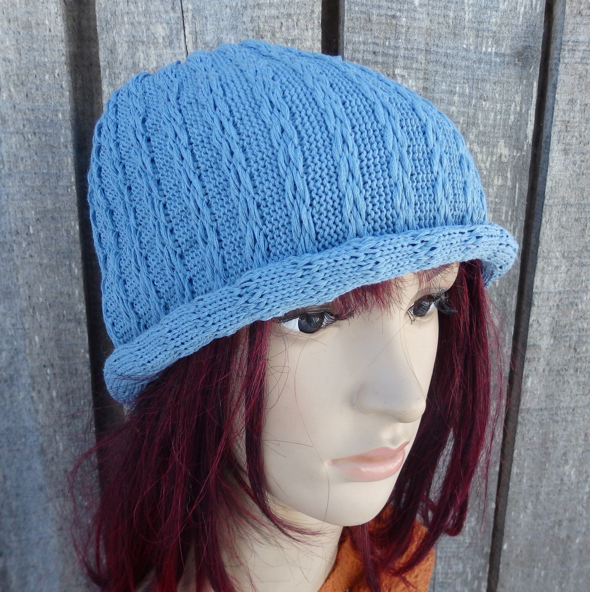 Blue knitted hat on a mannequin head against a wooden background