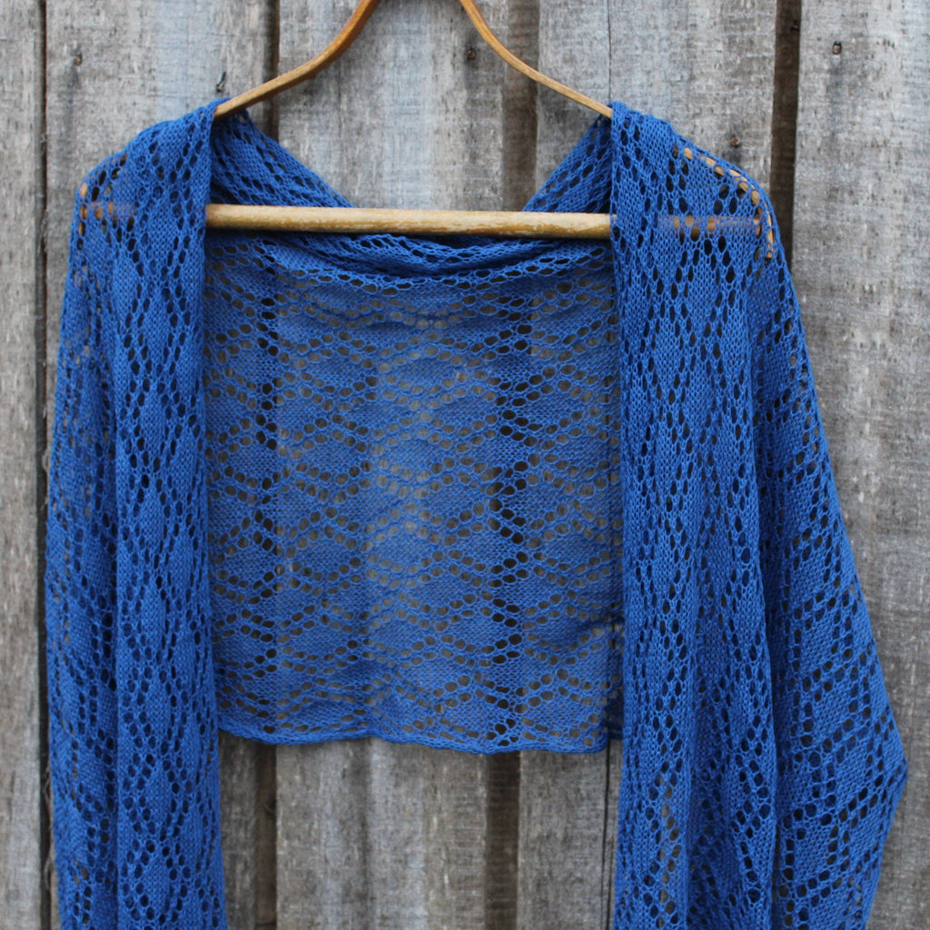 Blue knitted shawl on a wooden hanger against a wooden background