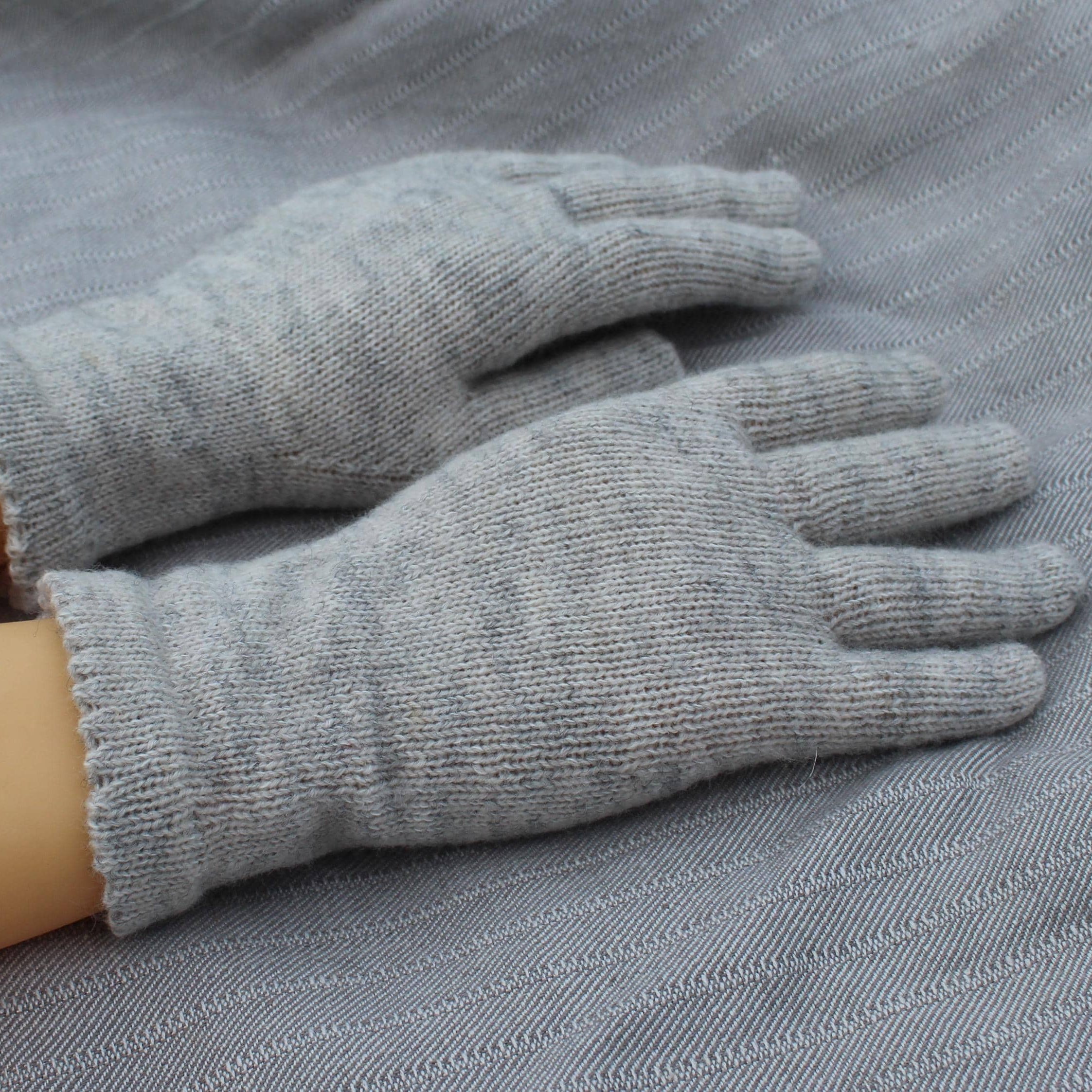 Gray gloves on a person's hands with a gray fabric background