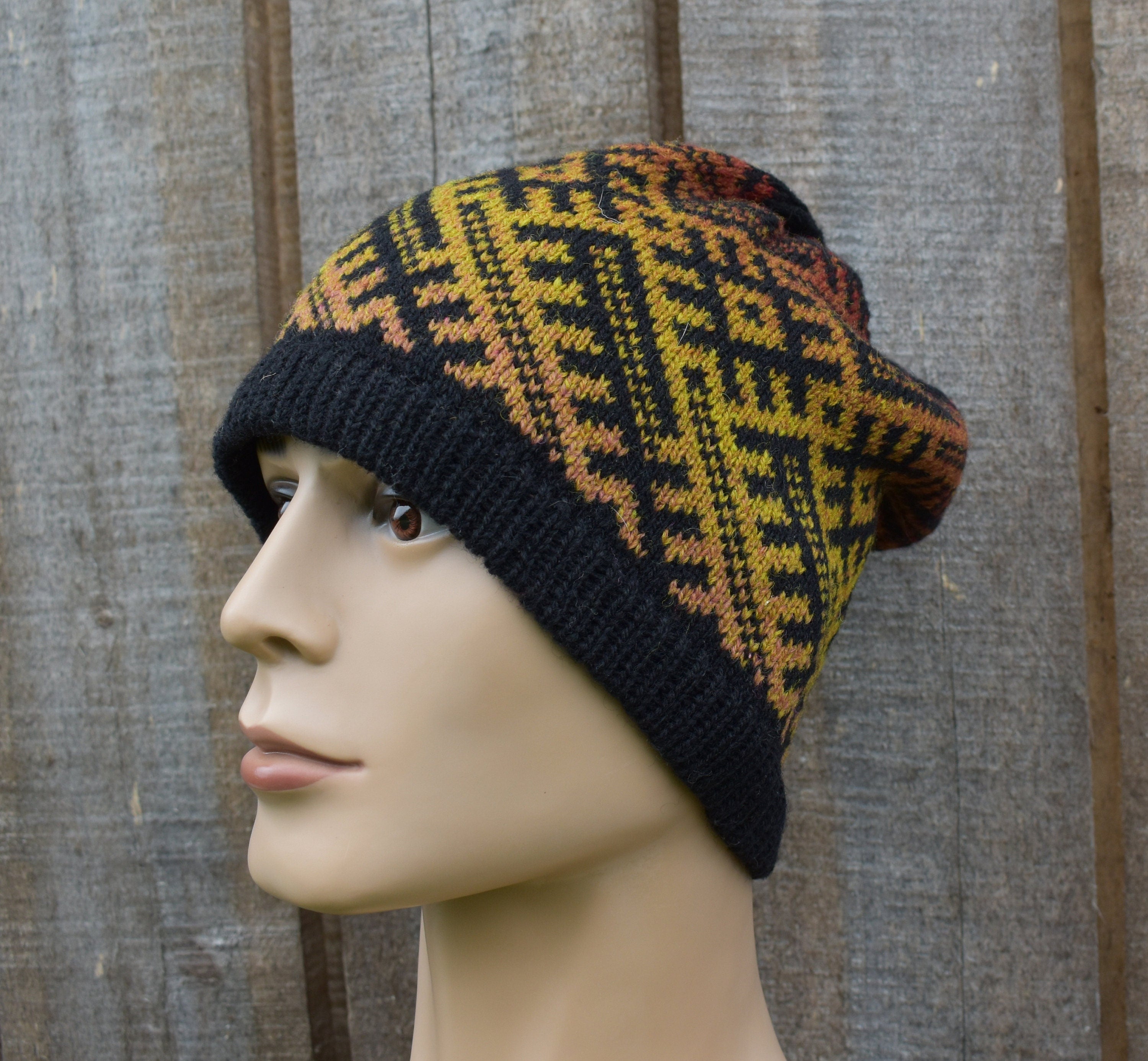 Knitted beanie with a geometric pattern on a mannequin head against a wooden background
