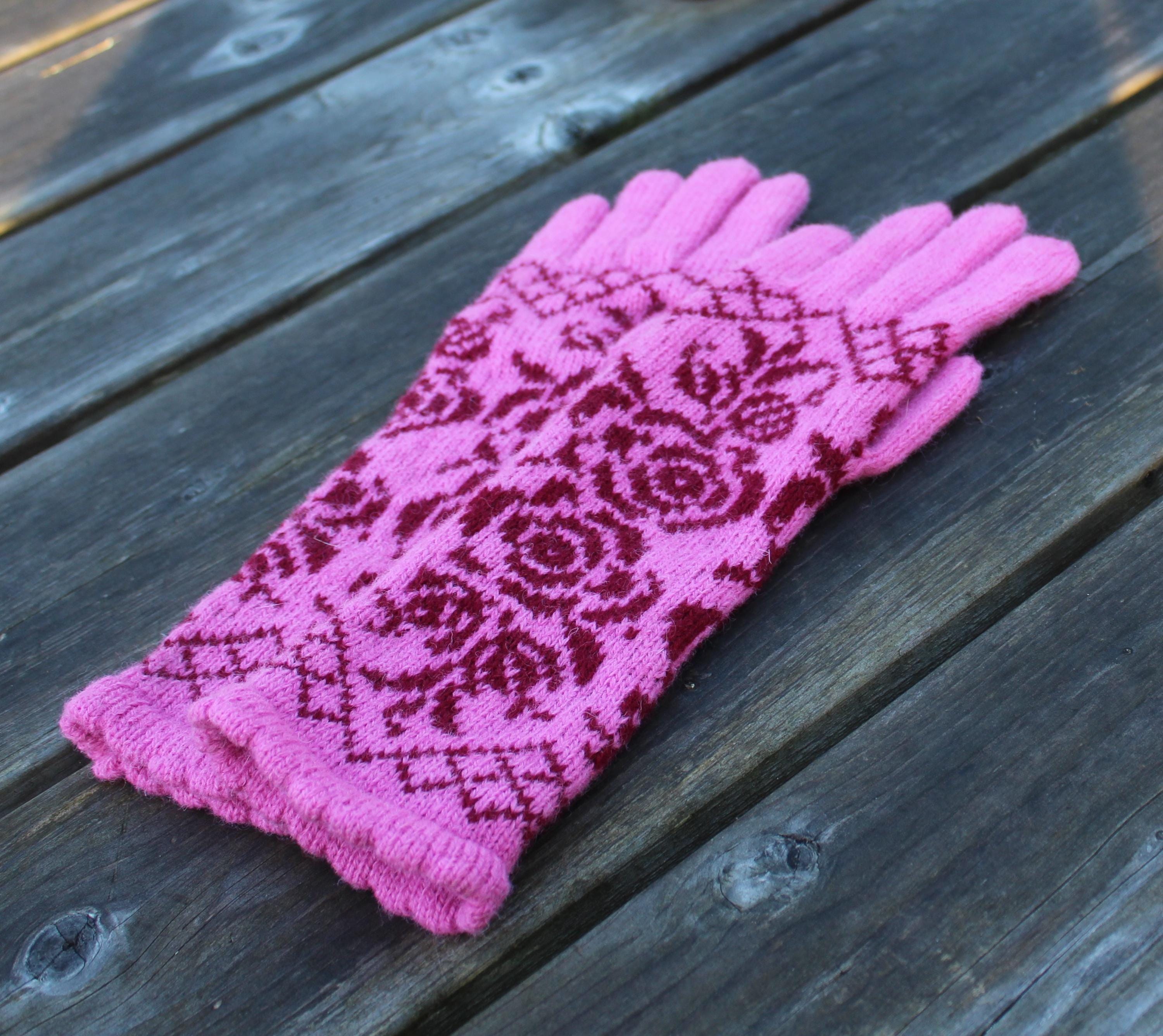 Pink gloves with red floral pattern on a wooden surface