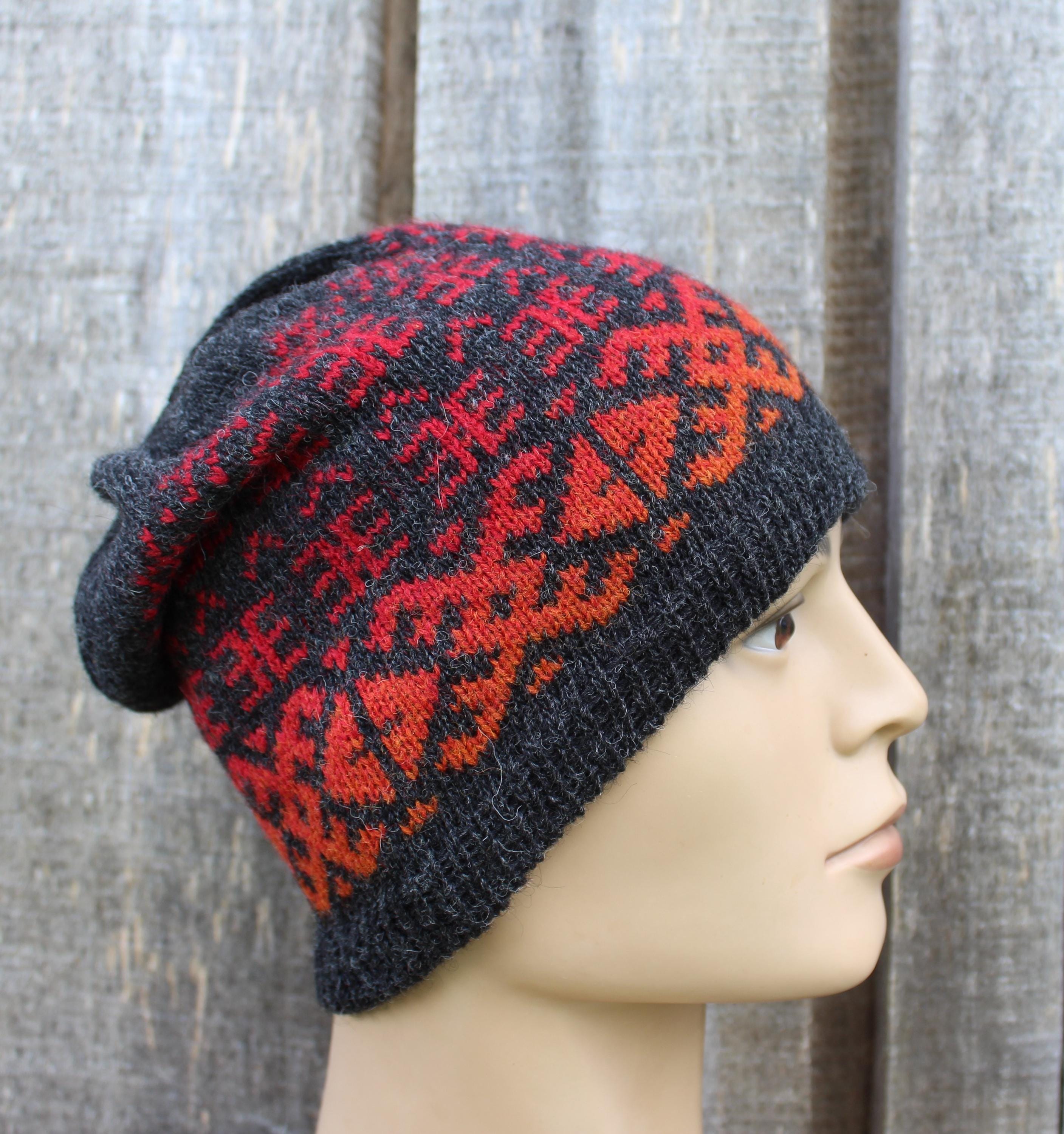 Knitted beanie with red and black pattern on a mannequin head against a wooden background