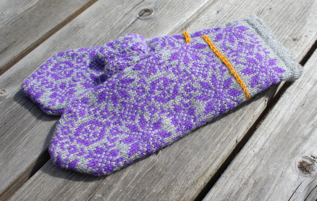 Pair of purple and gray patterned mittens on a wooden surface