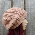 Knitted pink beanie on a mannequin head against a wooden background