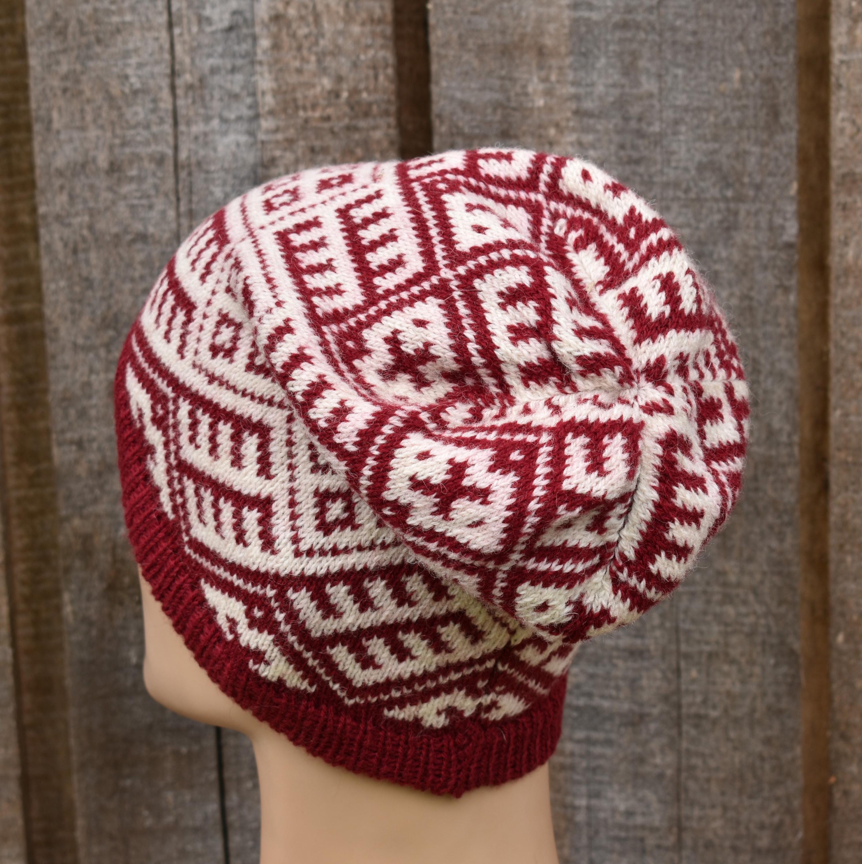 Knitted hat with red and white pattern on a wooden background