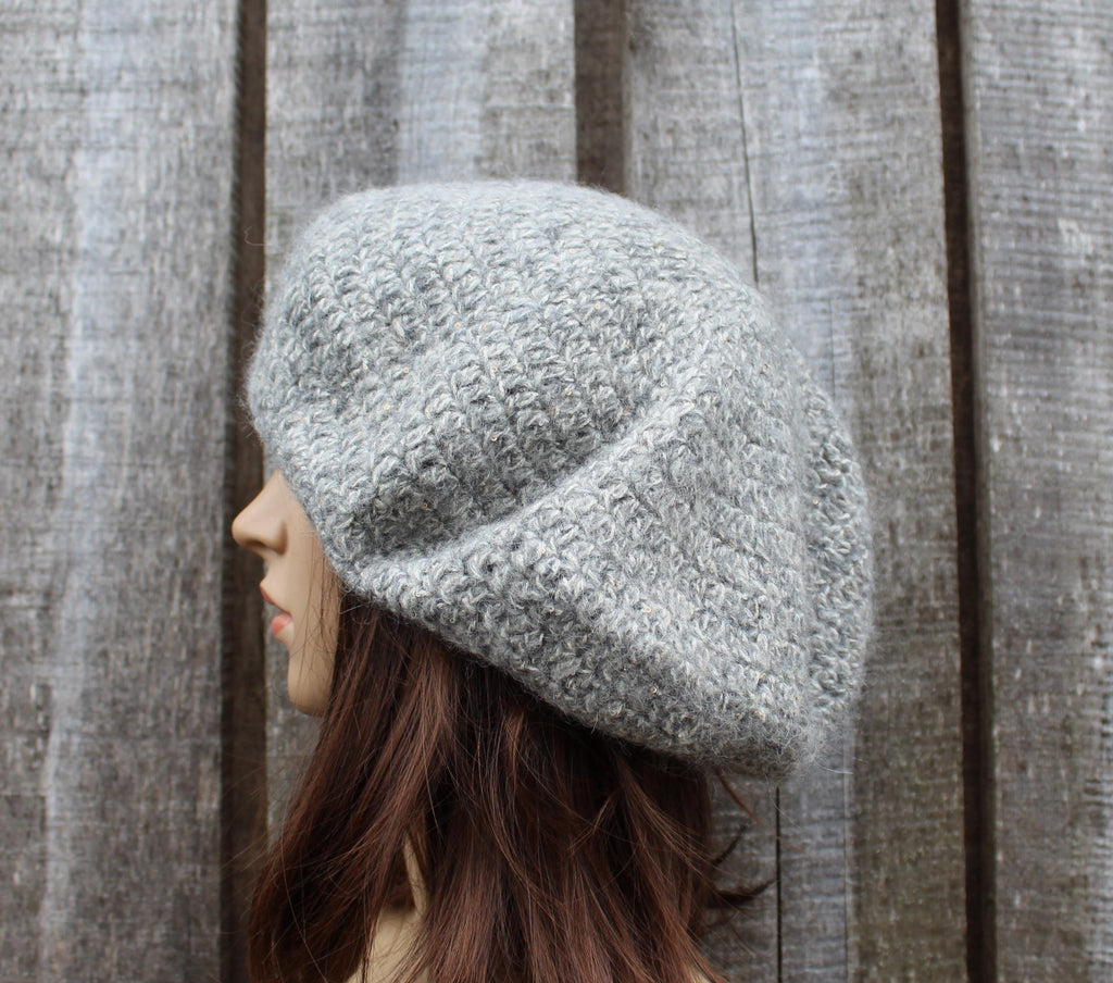 Person wearing a textured gray knit hat against a wooden background