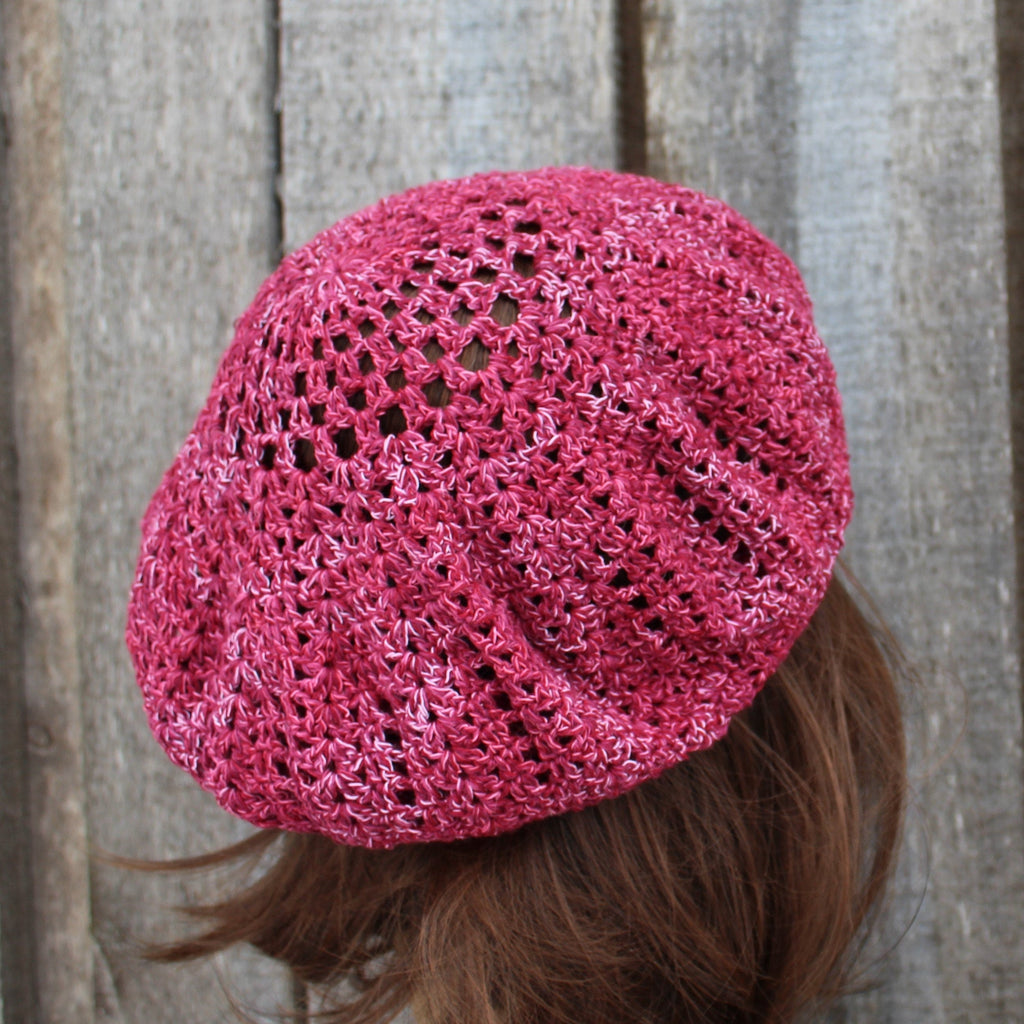 Pink knitted beret on a wooden background