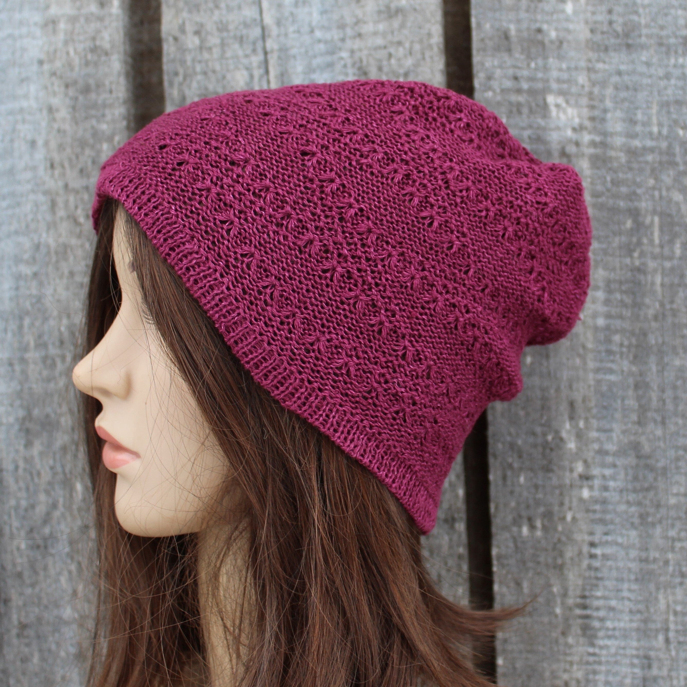 Mannequin head wearing a purple knitted beanie against a wooden background