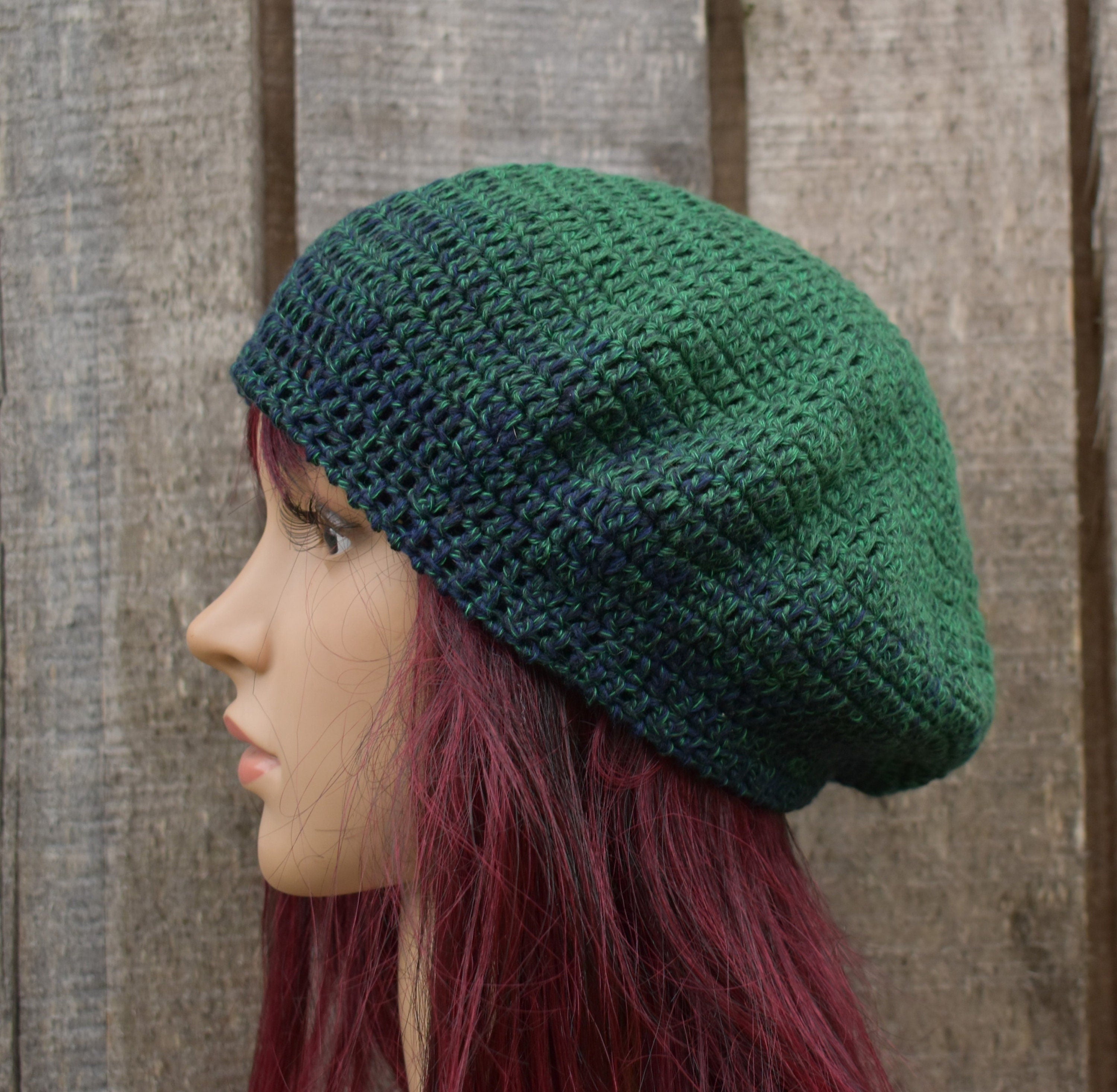 Green knitted beanie on a mannequin head against a wooden background