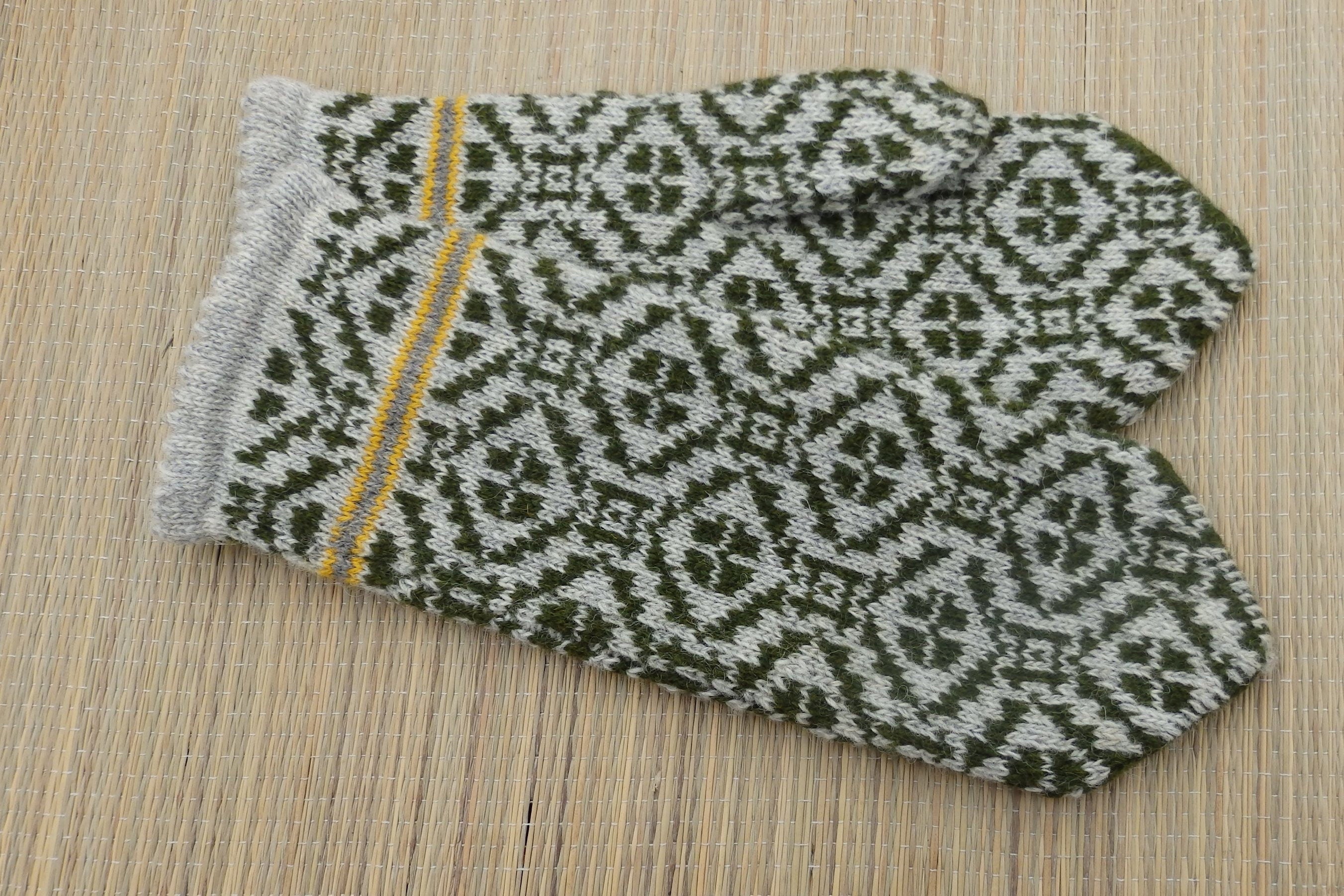 Knitted mittens with a geometric pattern on a wooden surface