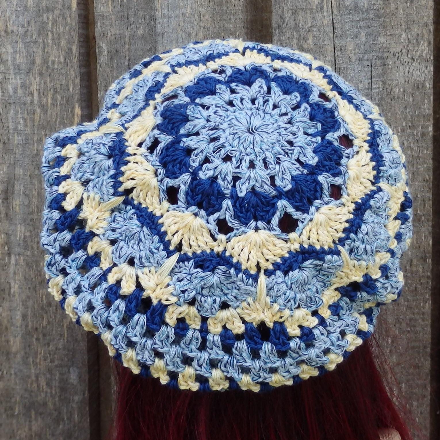 Blue and beige crocheted hat on a wooden background