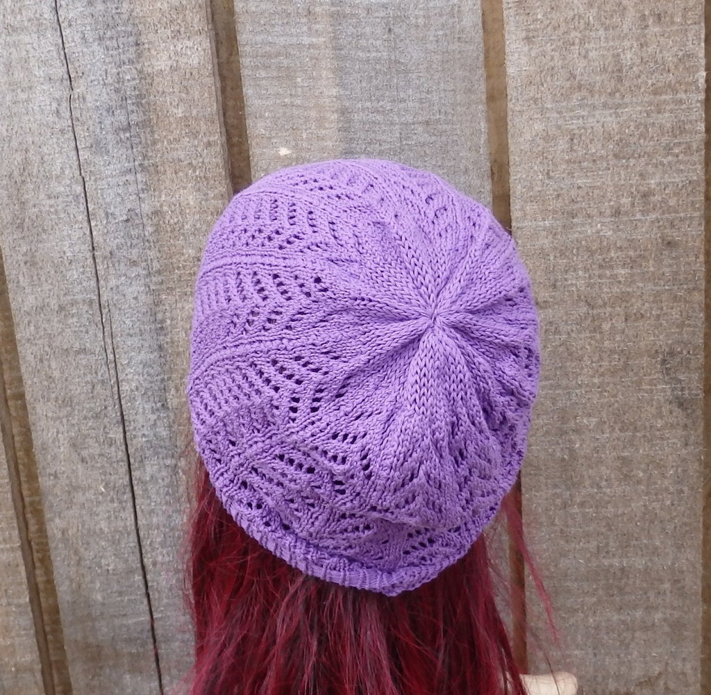 Purple knitted hat on a person with red hair against a wooden background