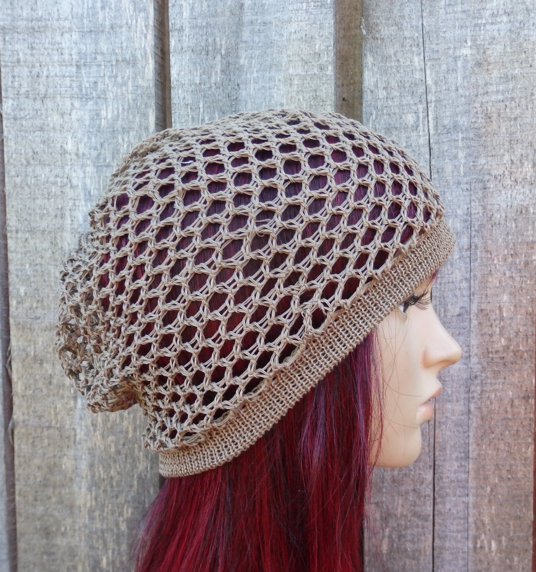 Person wearing a beige crochet hat against a wooden background