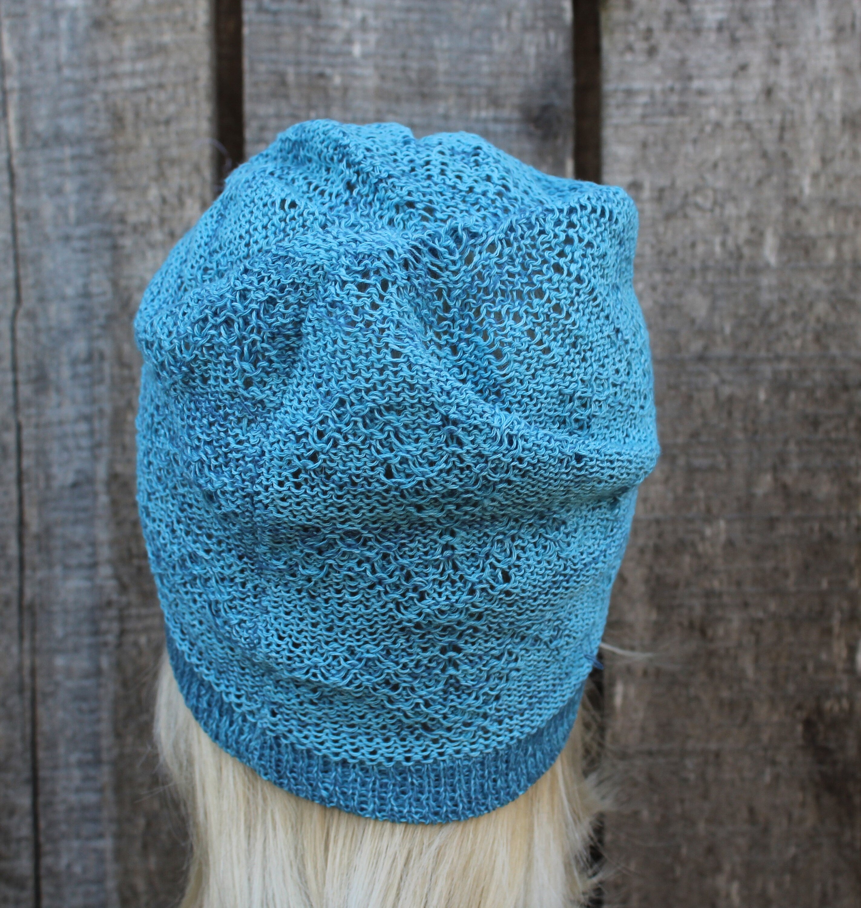 Blue knitted hat on a mannequin head against a wooden background