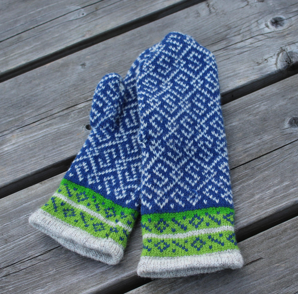 Pair of blue and green patterned mittens on a wooden surface