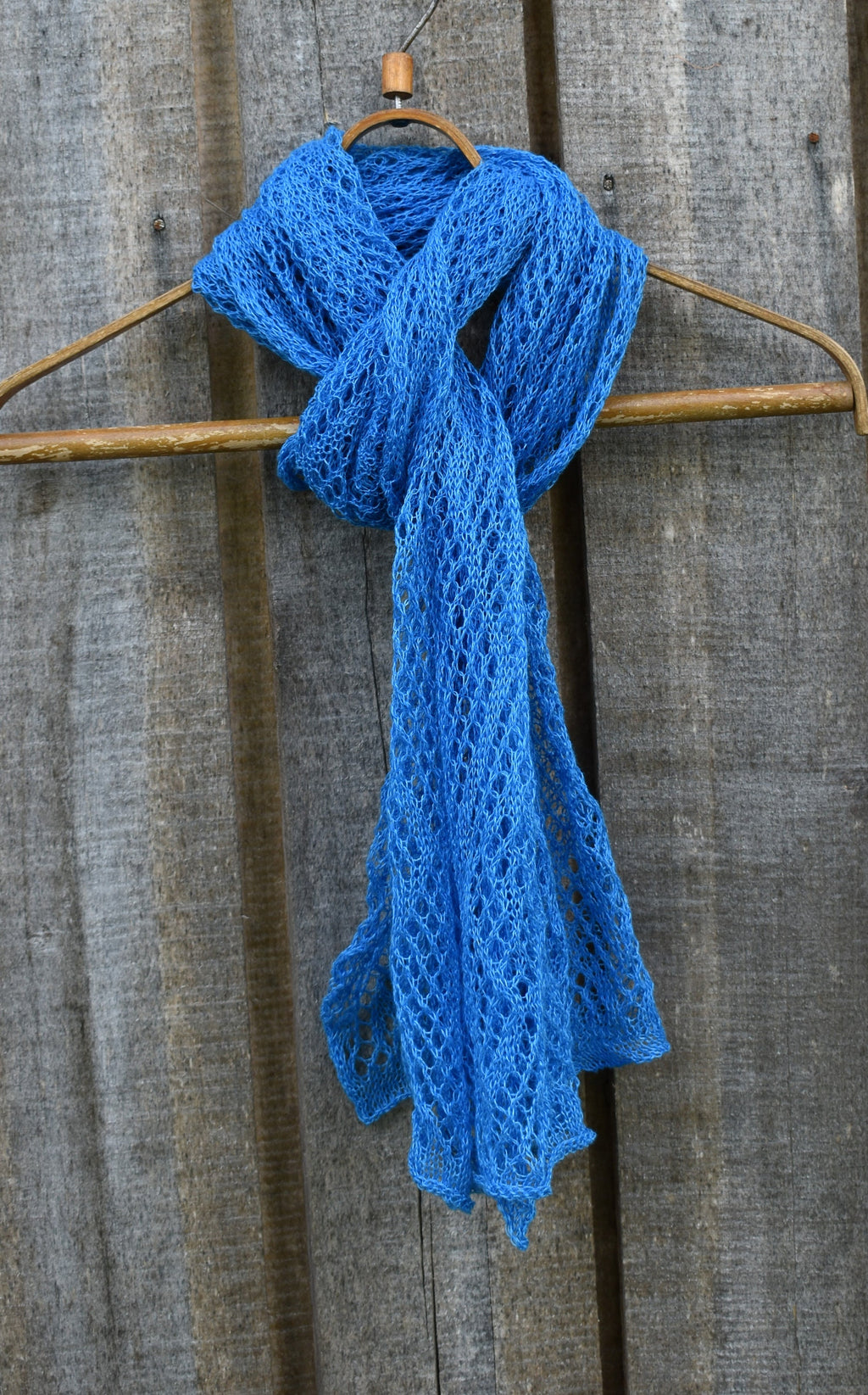 Blue linen scarf on a wooden hanger against a rustic wooden background
