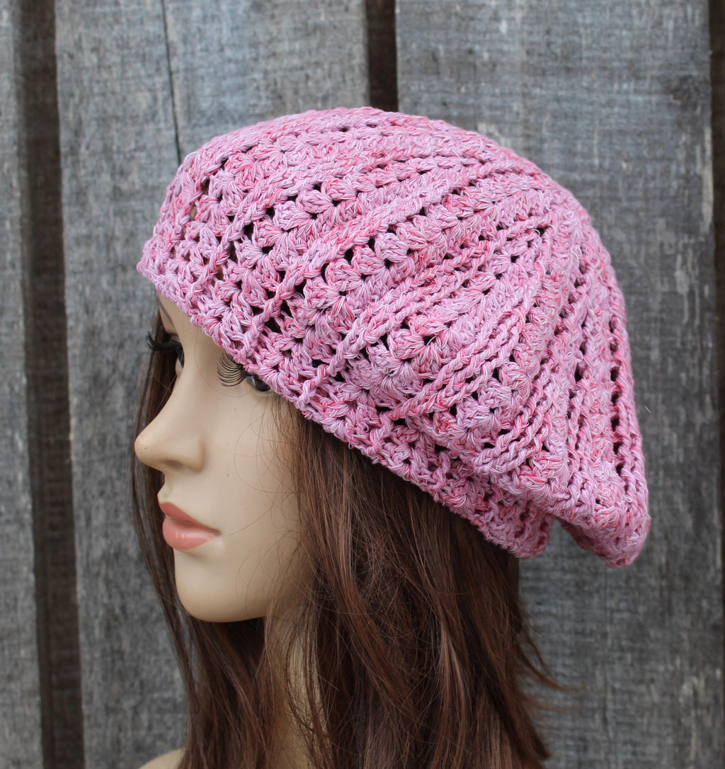 Pink crocheted beanie on a mannequin head against a wooden background