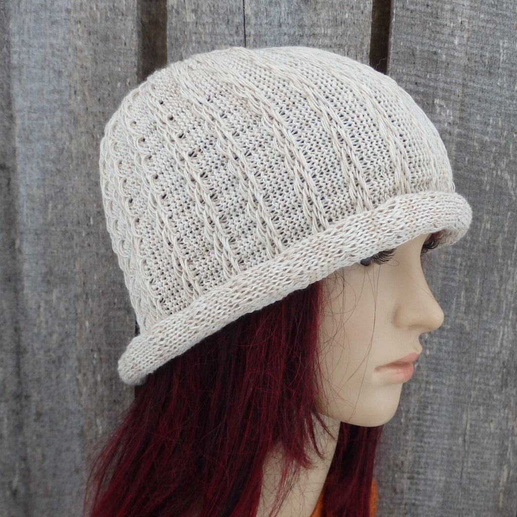 Knitted beige hat on a mannequin head against a wooden background