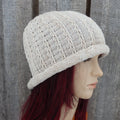 Knitted beige hat on a mannequin head against a wooden background