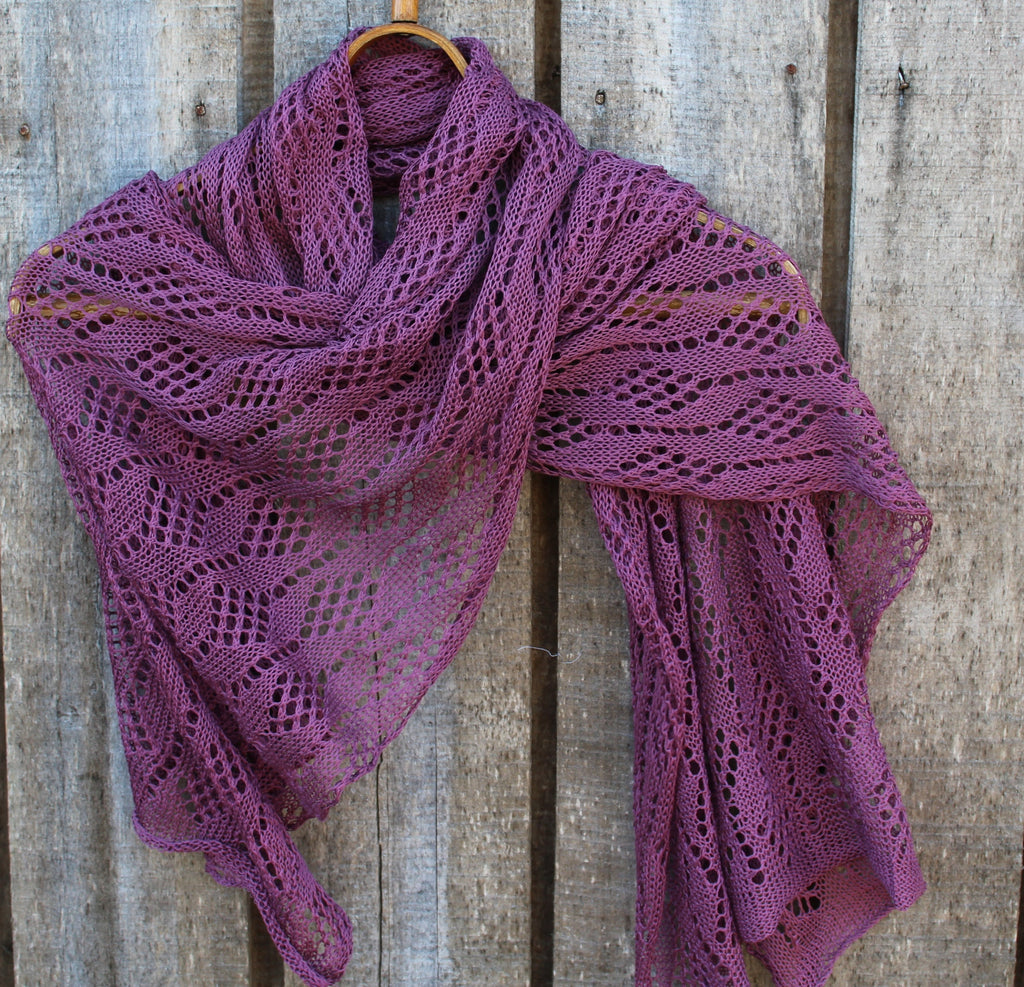 Purple knitted shawl draped over a wooden surface