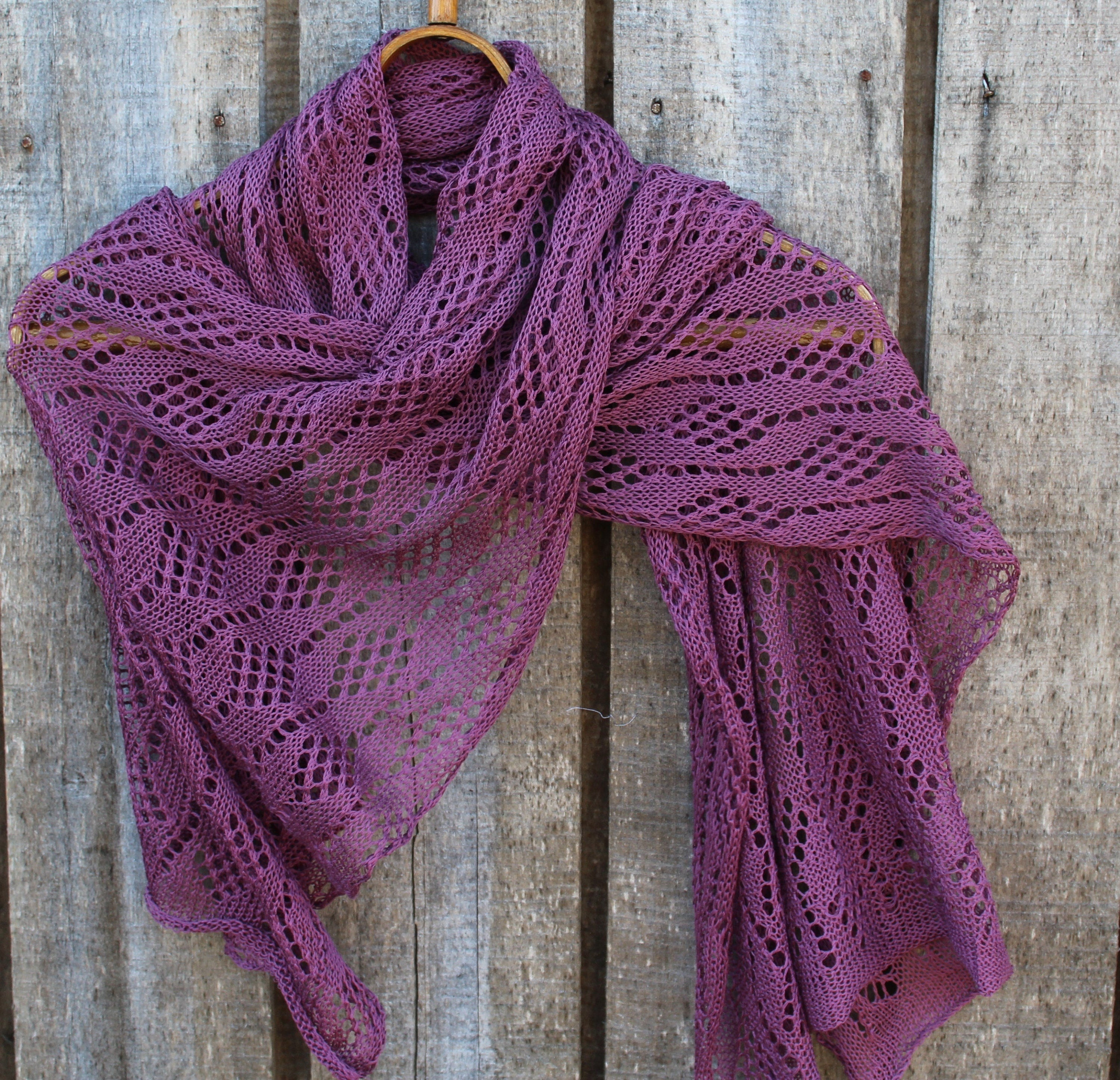 Purple knitted shawl draped over a wooden surface