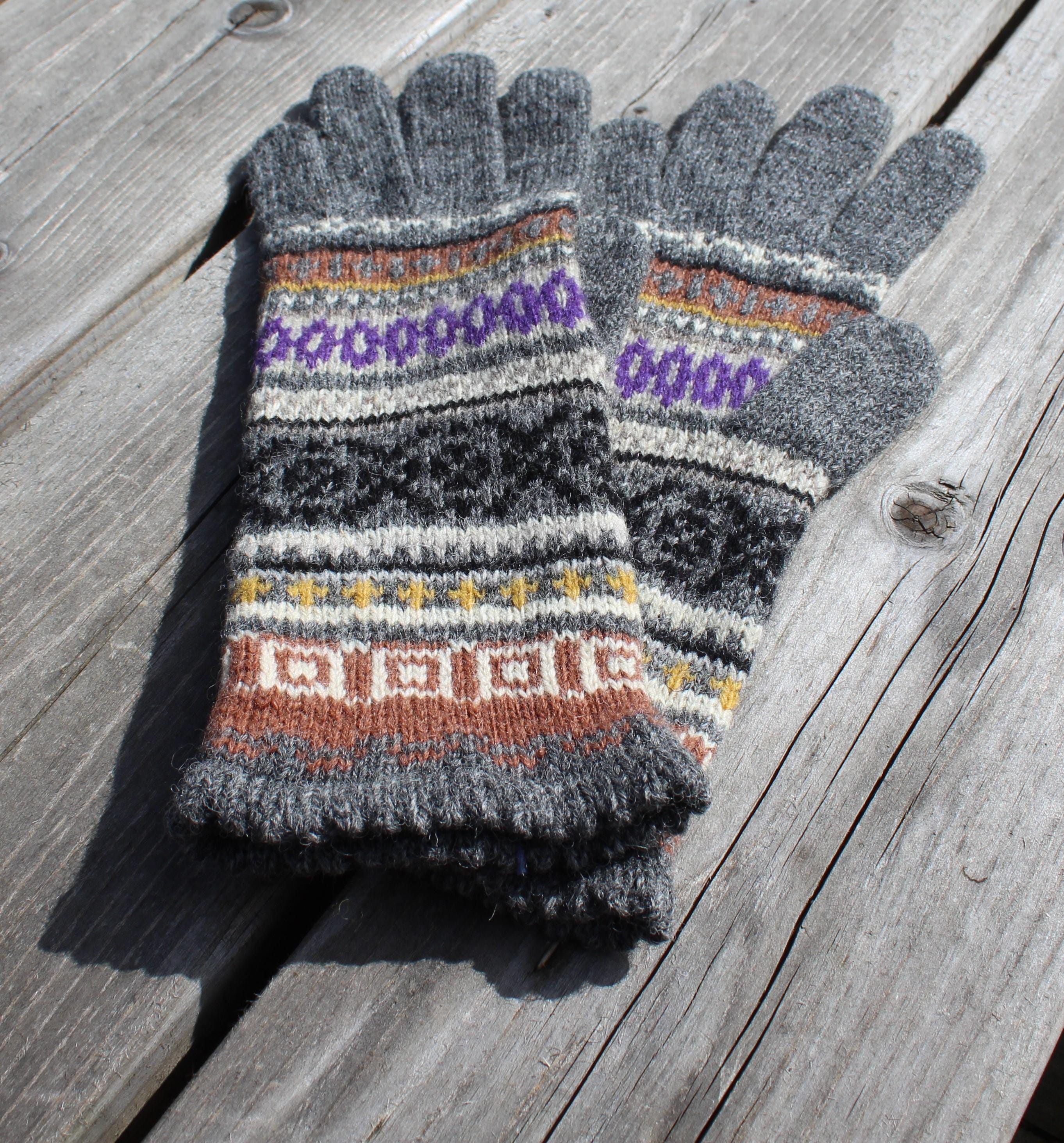 Pair of gray gloves with colorful pattern on a wooden surface