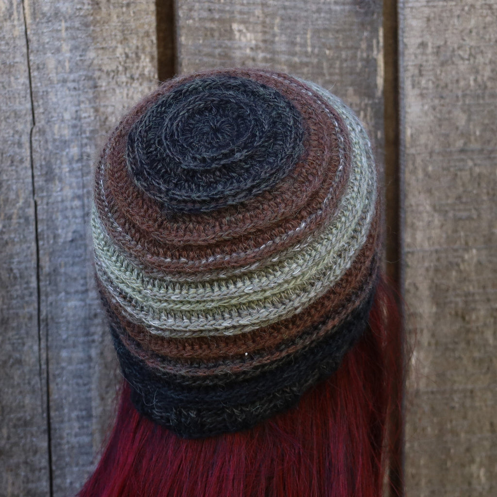 Multicolored knitted hat with tassels on a wooden background