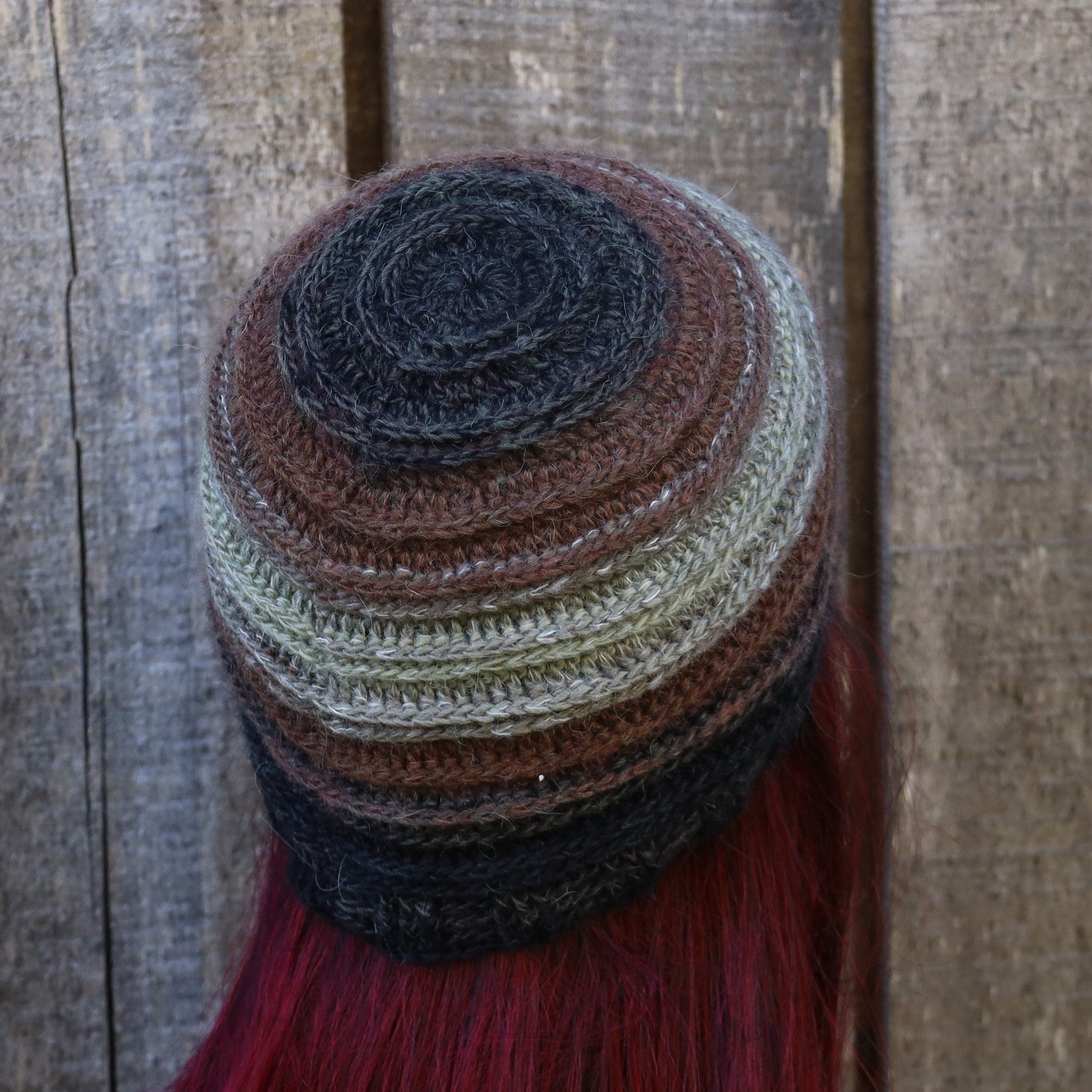 Multicolored knitted hat with tassels on a wooden background