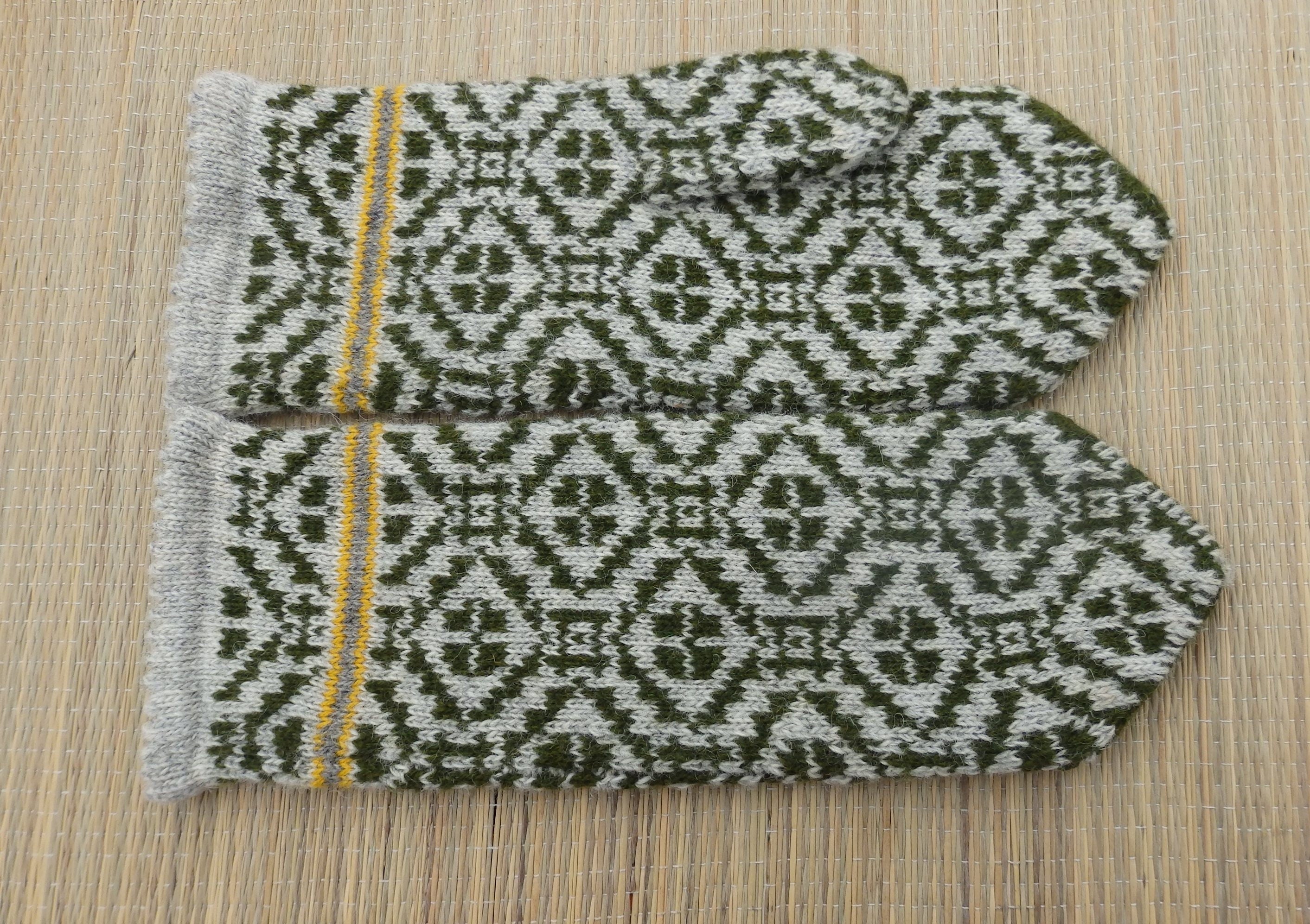 Pair of knitted mittens with a geometric pattern on a wooden surface