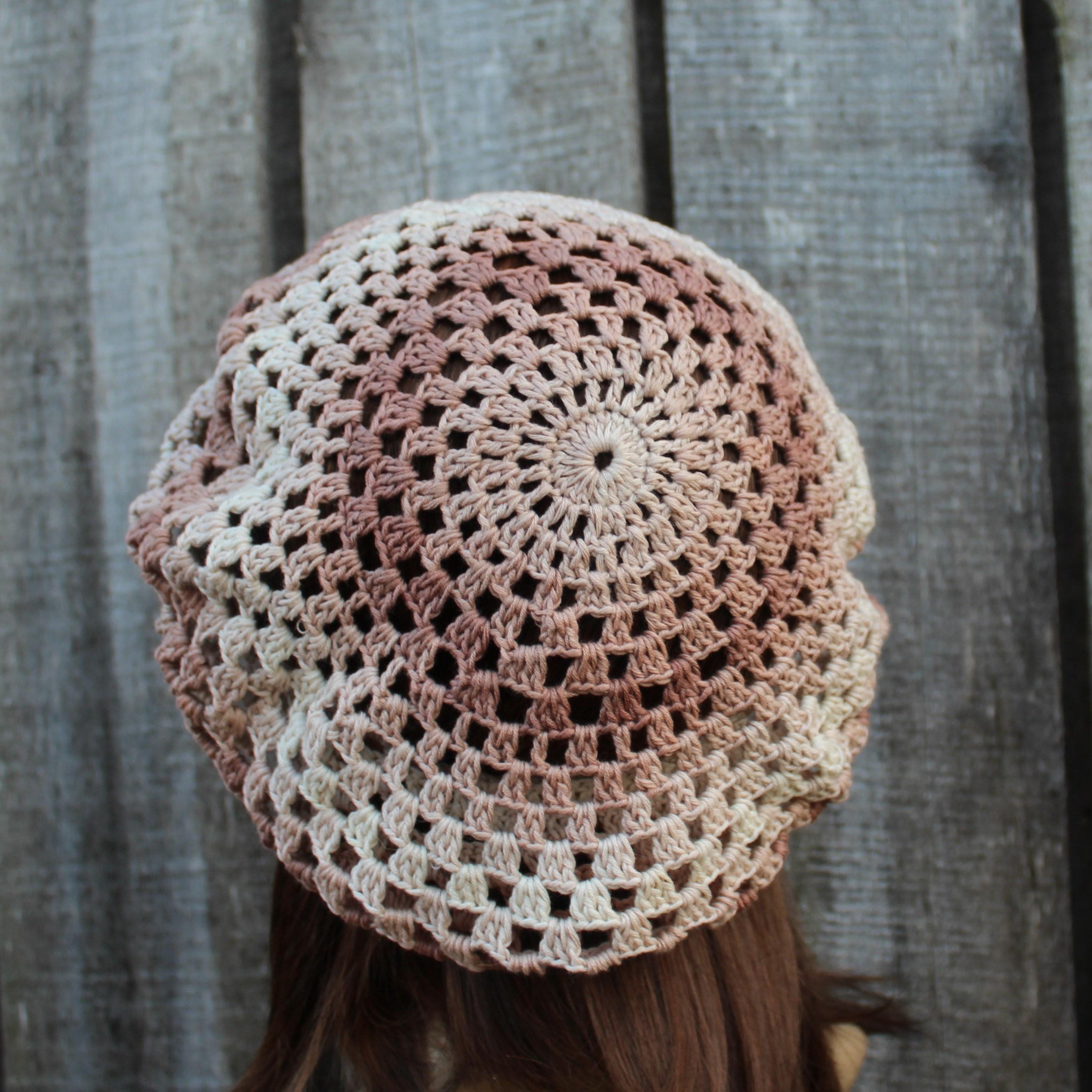 Crocheted hat with a gradient pattern worn by a person against a wooden background