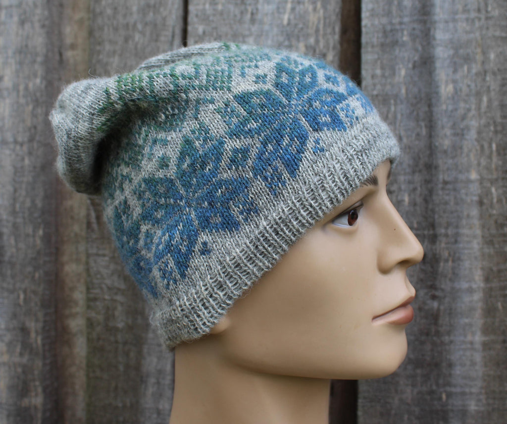 Knitted hat with blue floral pattern on a mannequin head against a wooden background