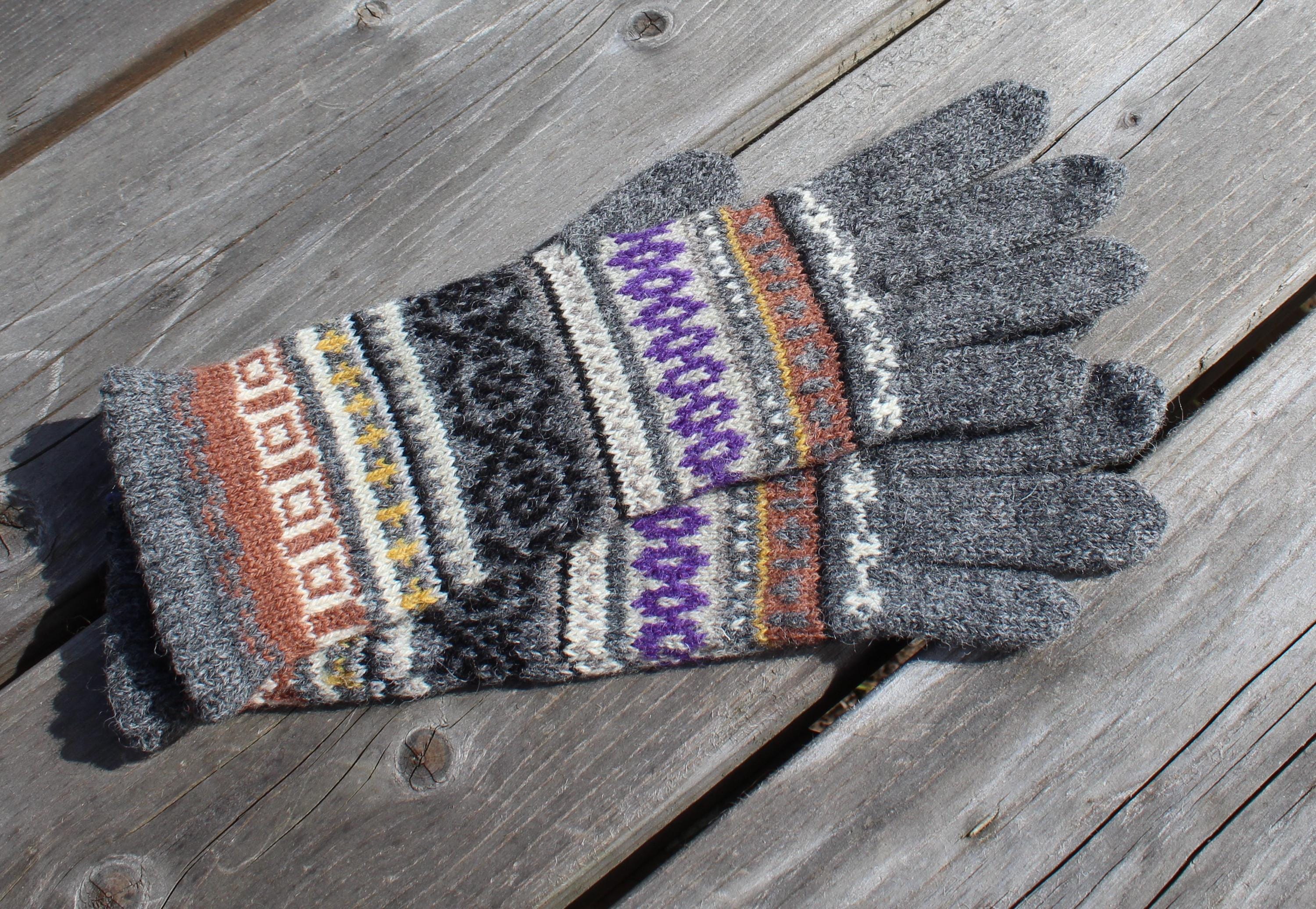 Pair of gray gloves with colorful pattern on a wooden surface