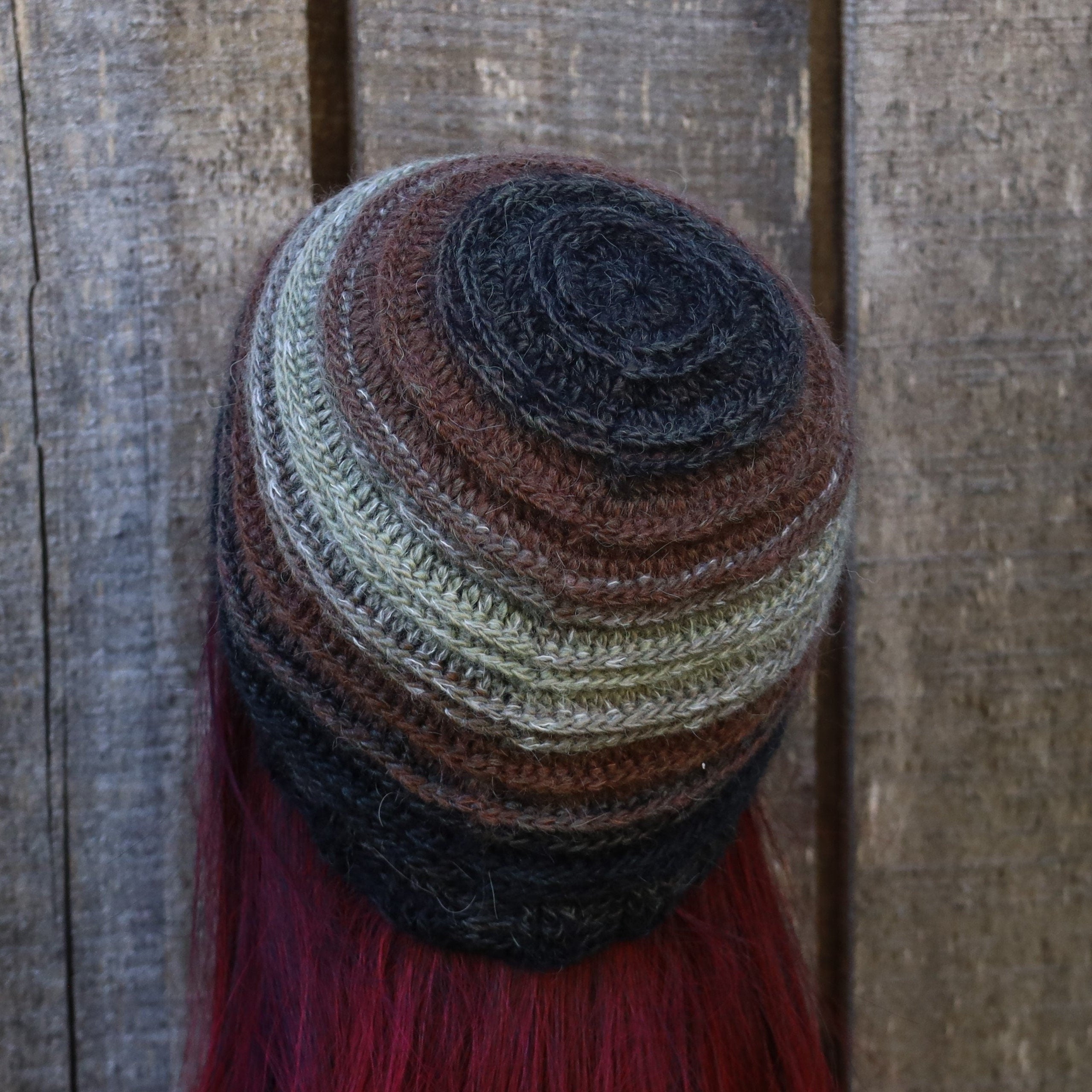 Stack of multicolored knit hats on a wooden surface