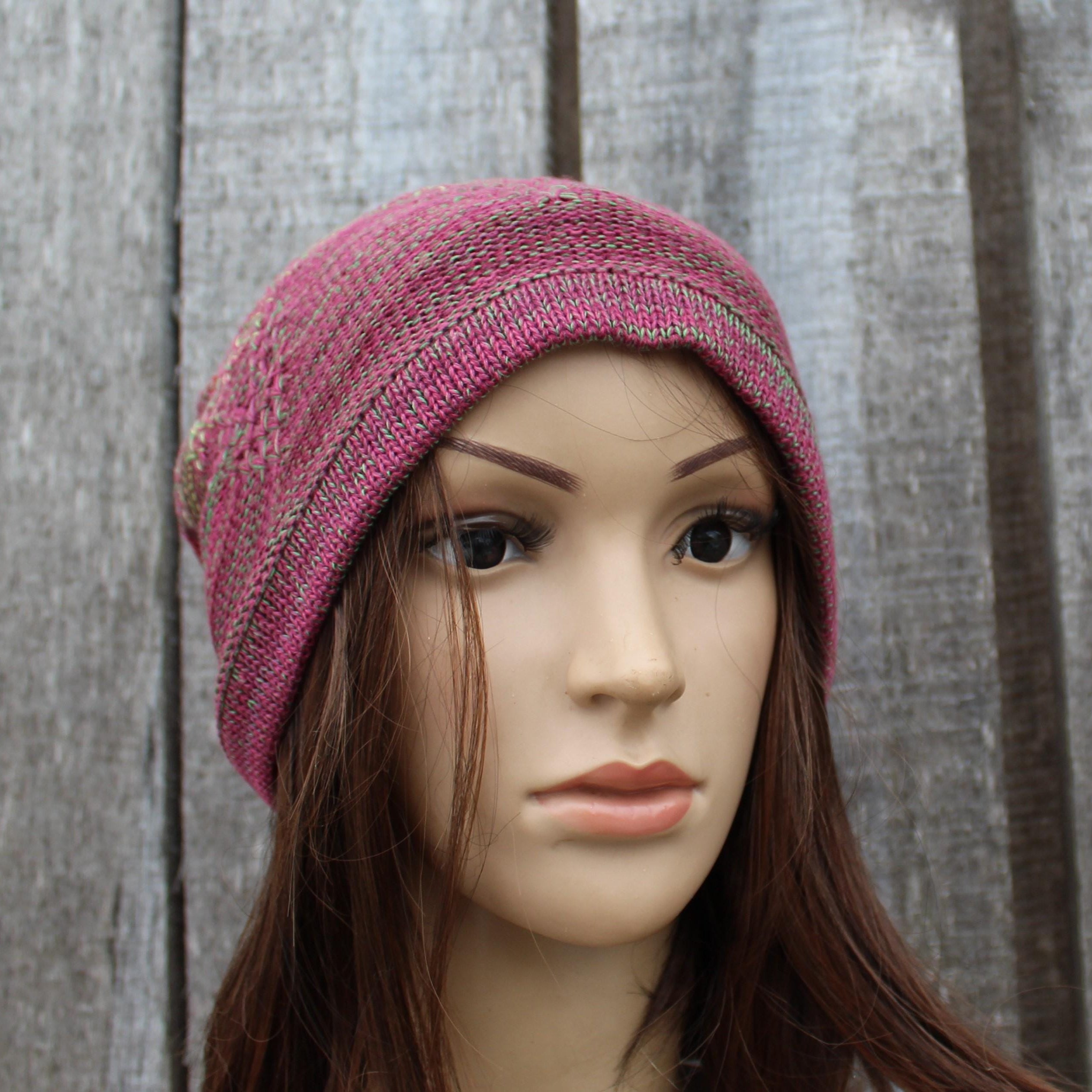 Mannequin head wearing a pink knitted beanie against a wooden background