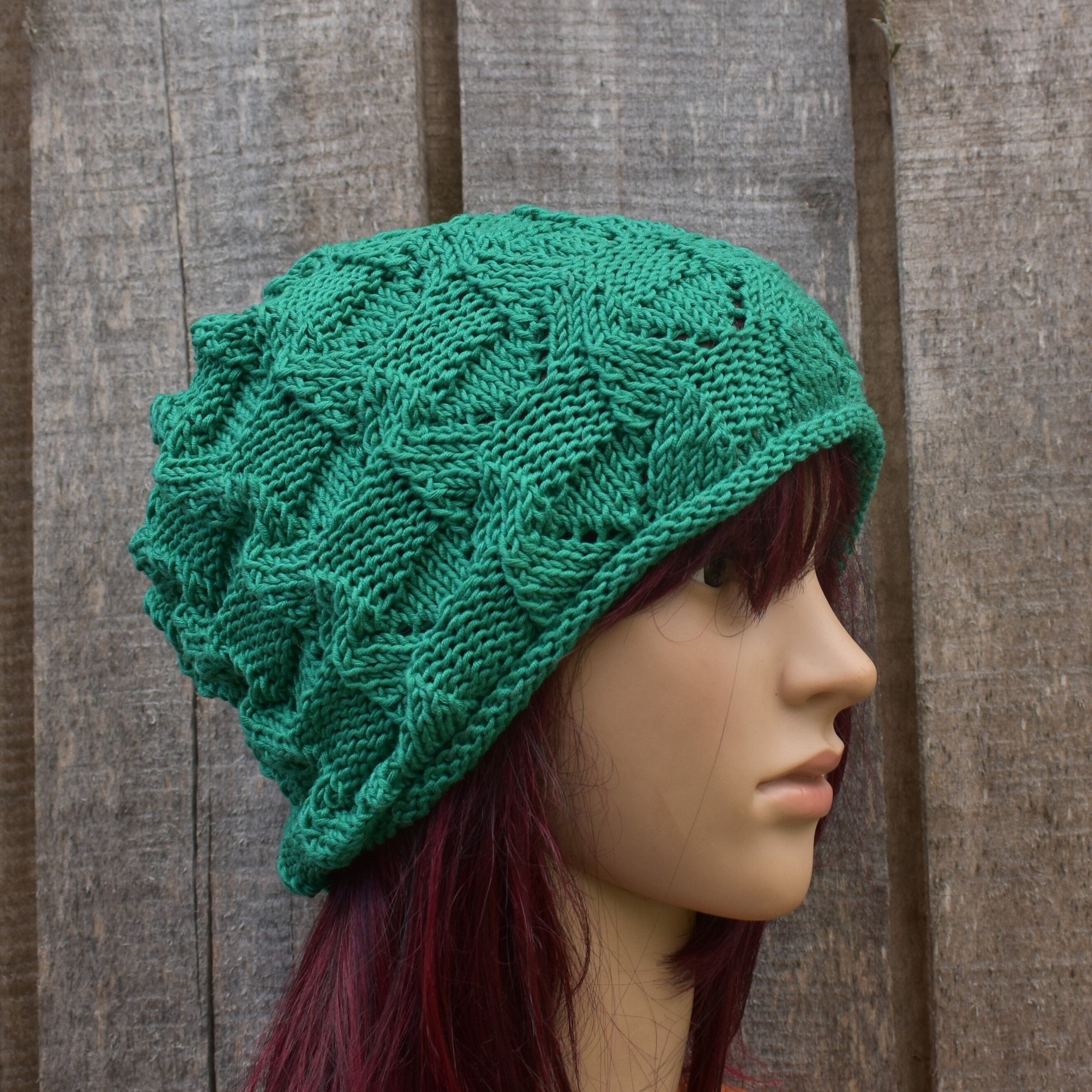 Green knitted hat on a mannequin head against a wooden background