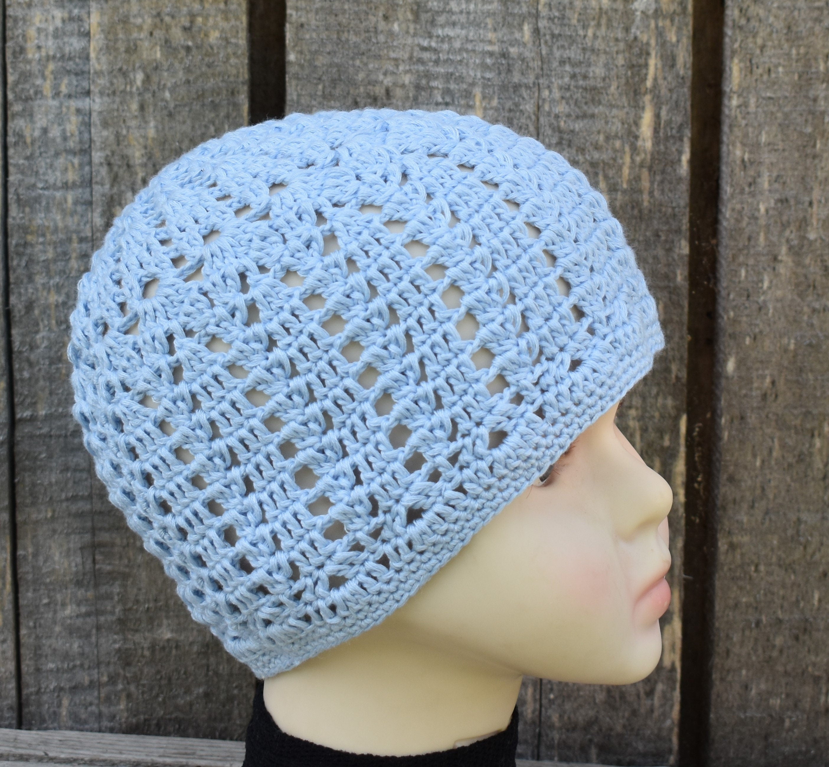 Light blue crochet hat on a mannequin head against a wooden background