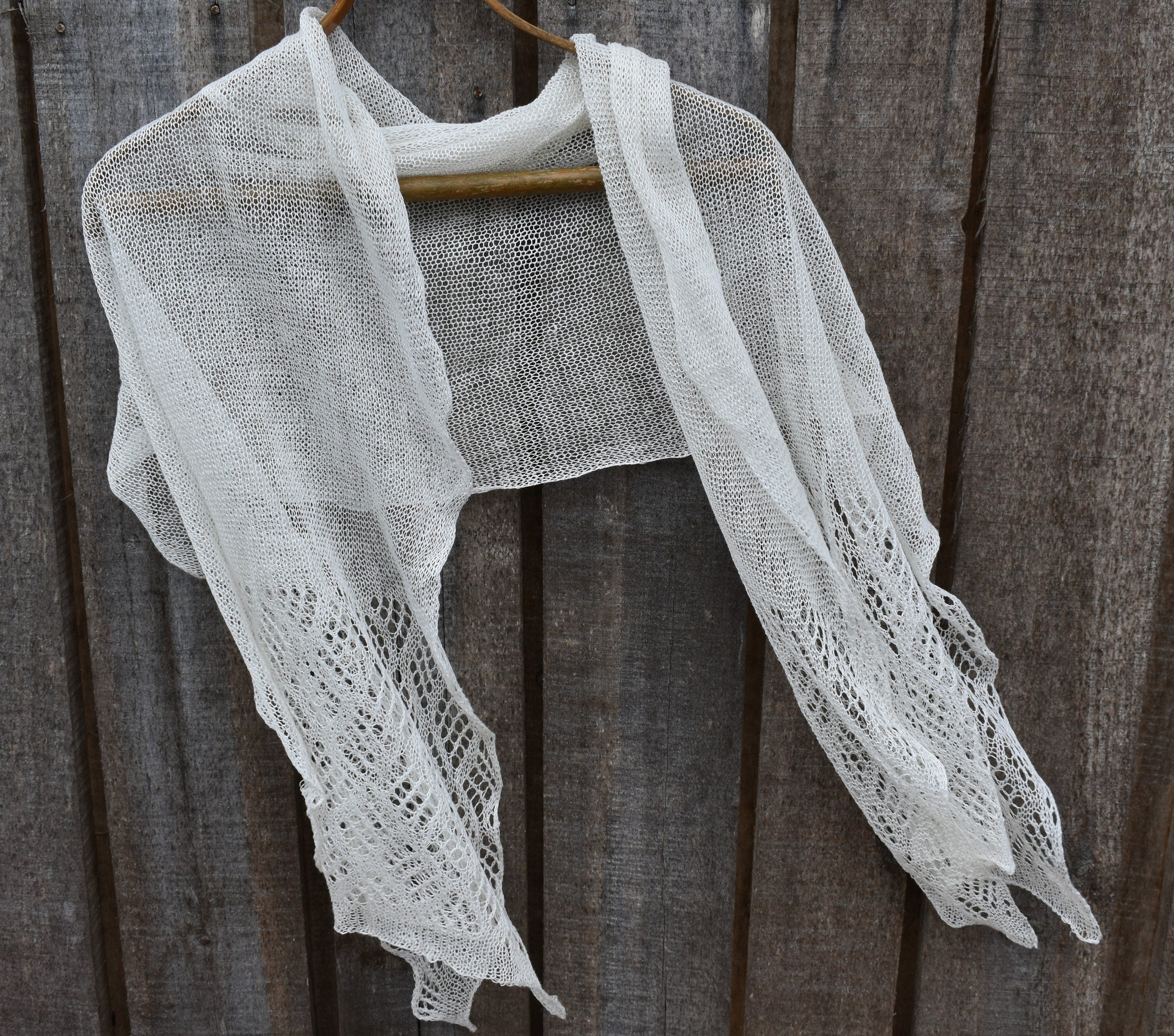 White lace shawl draped over a wooden hanger against a wooden background