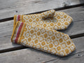Pair of knitted mittens with a floral pattern on a wooden surface