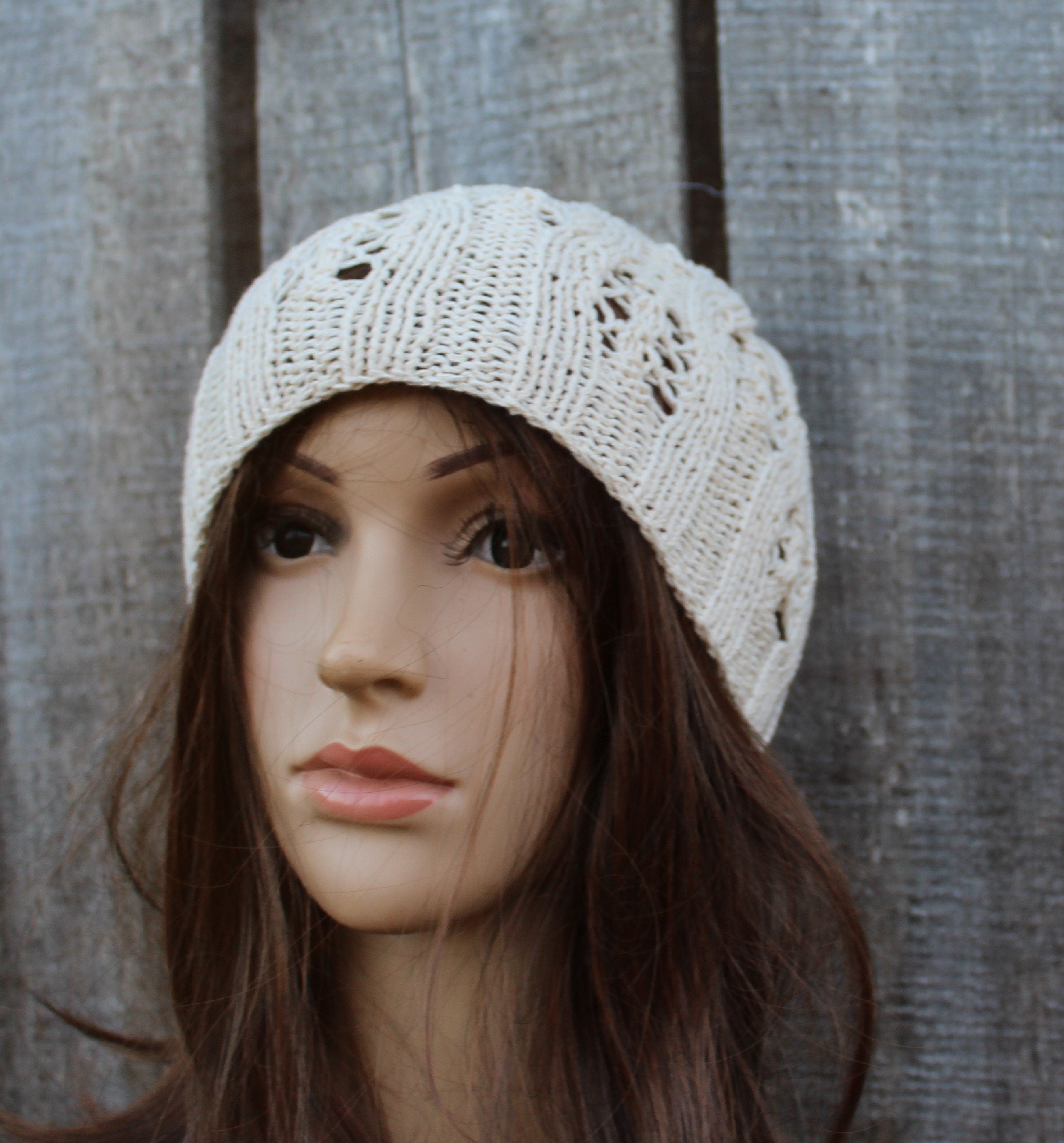 Mannequin head wearing a knitted beige hat against a wooden background