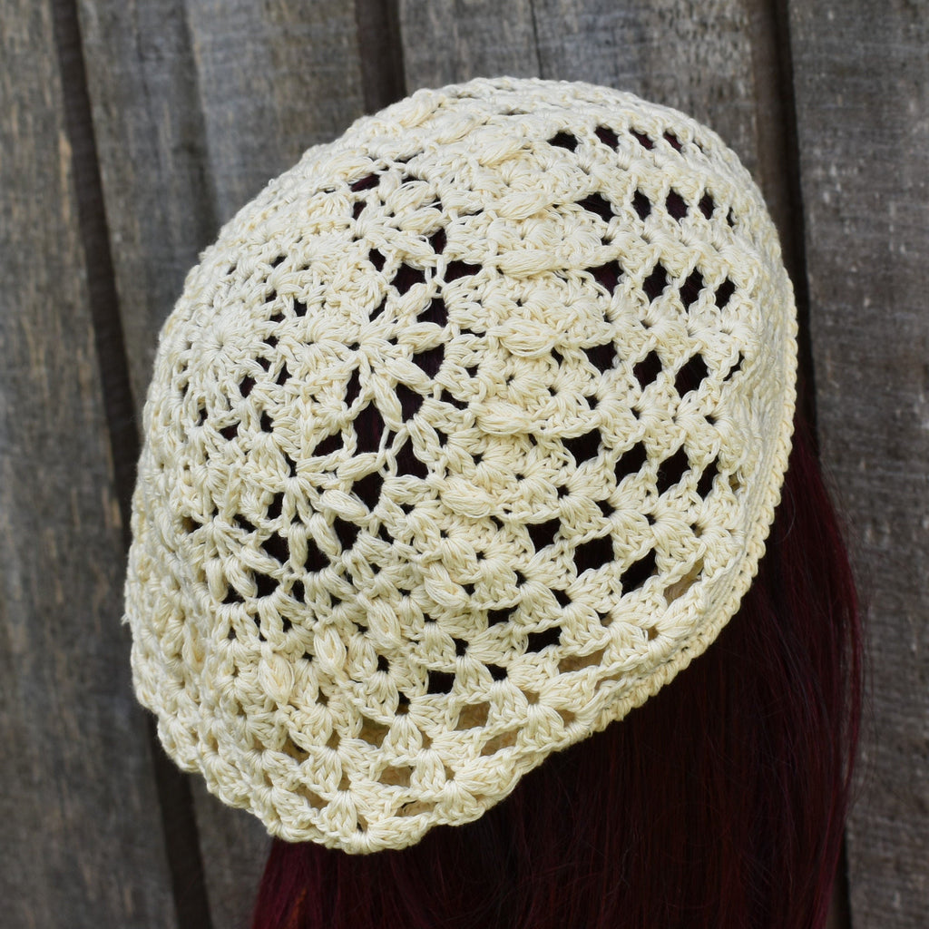 Crocheted beige headscarf on a person against a wooden background