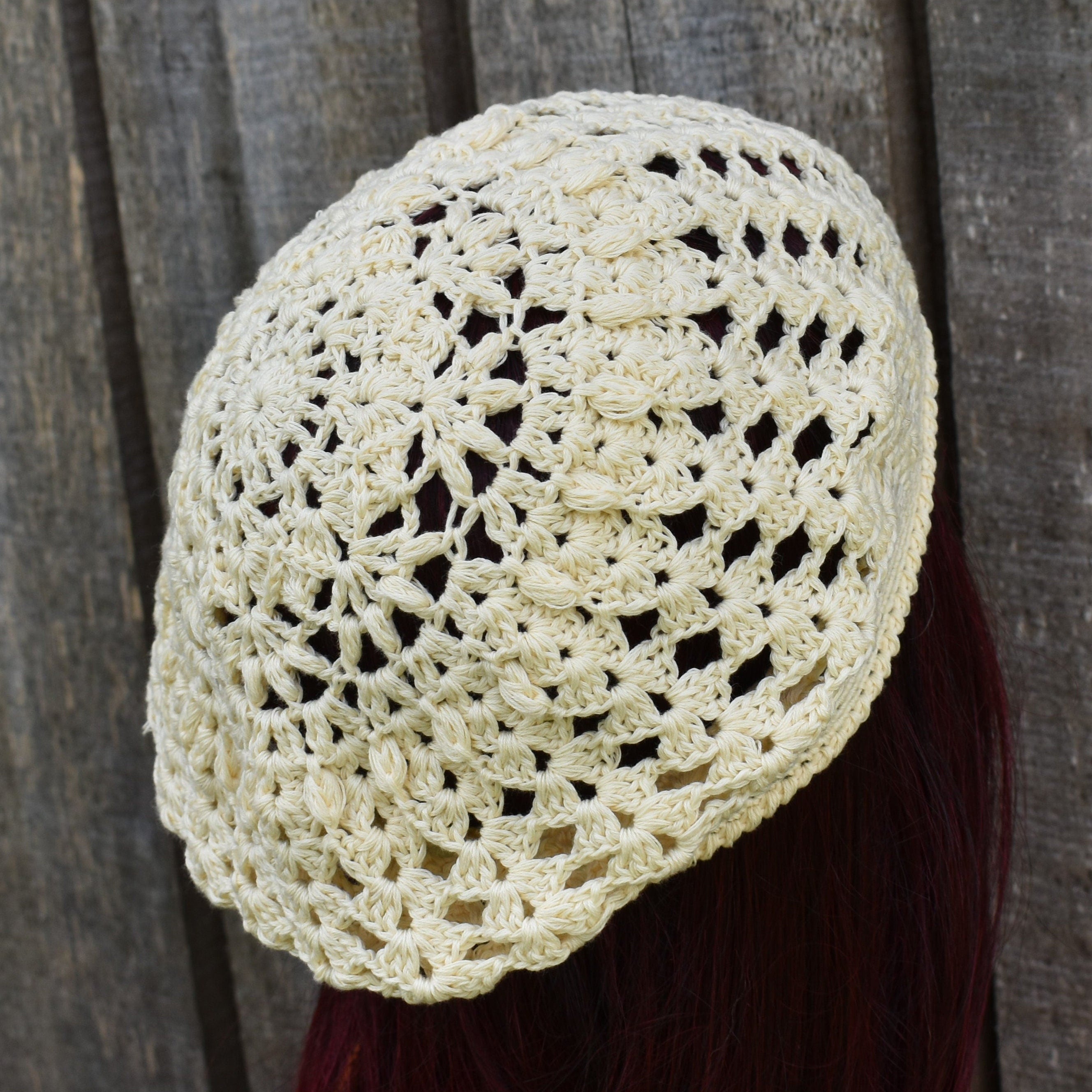 Crocheted beige headscarf on a person against a wooden background