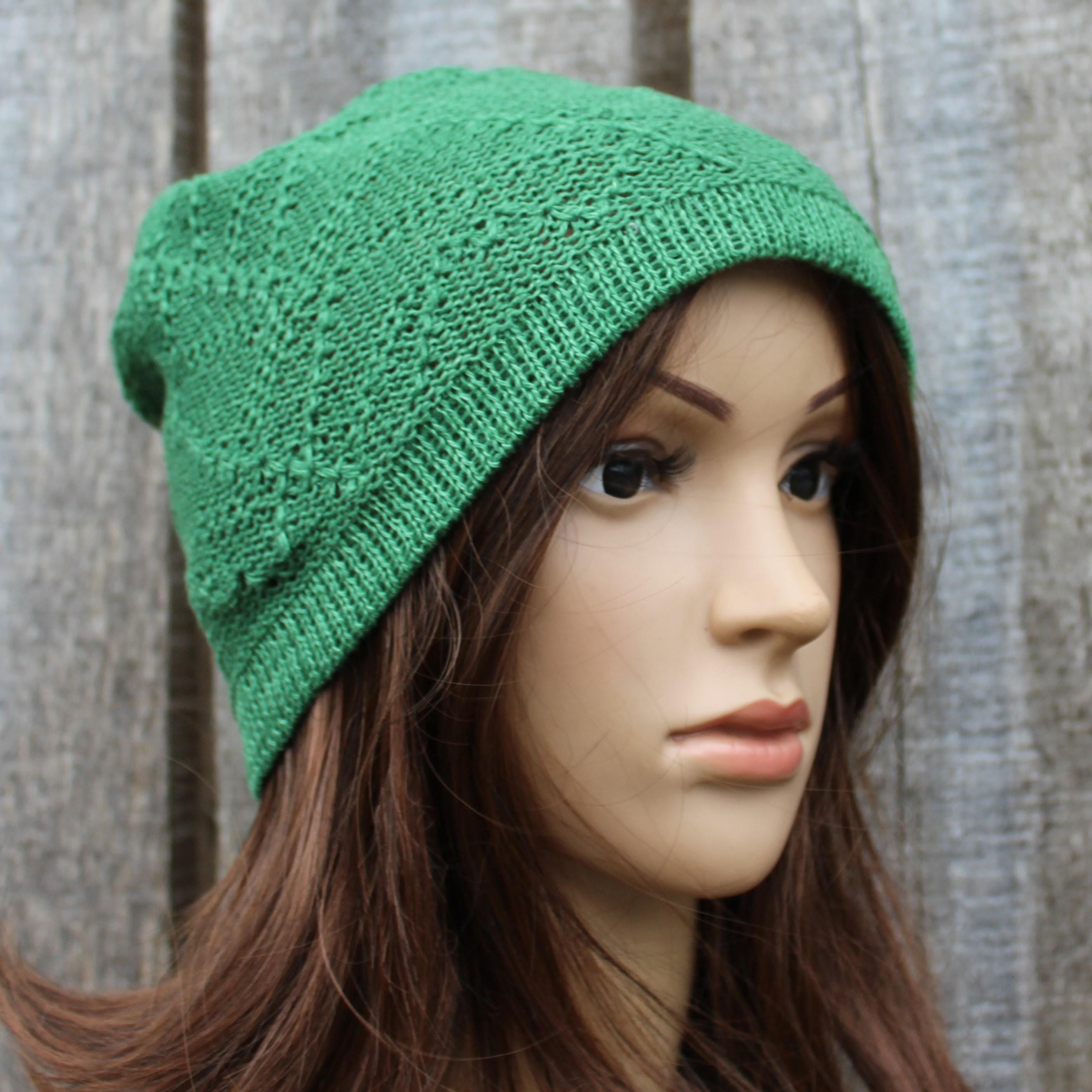 Green knitted beanie on a mannequin head against a wooden background