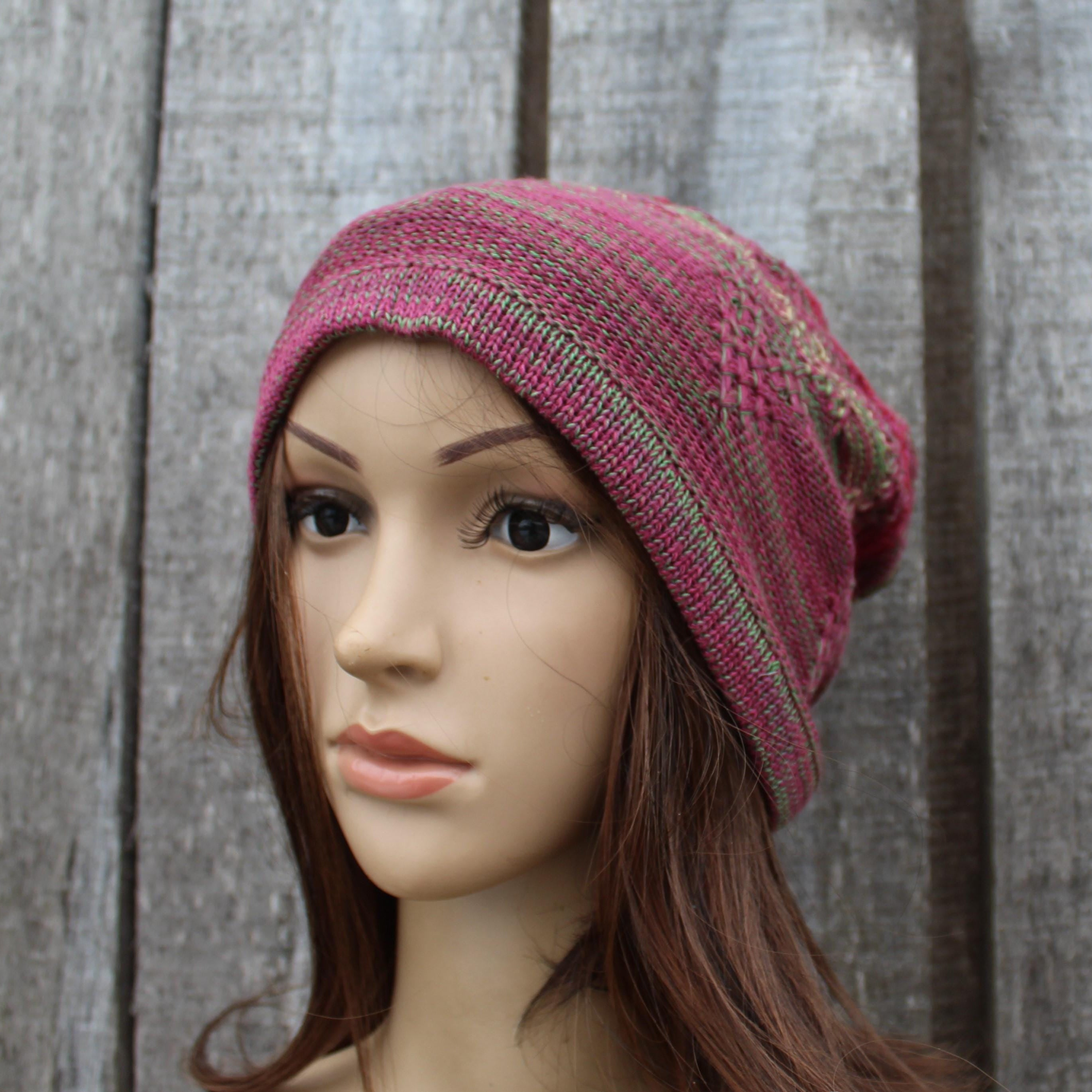 Mannequin head wearing a pink knit beanie against a wooden background