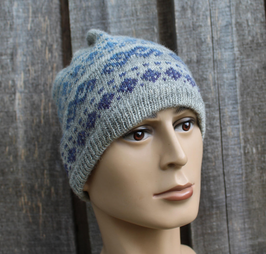 Gray knit hat with blue pattern on a mannequin head against a textured gray background